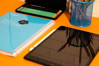 A desk with a laptop, notebook, and a cup of pencils