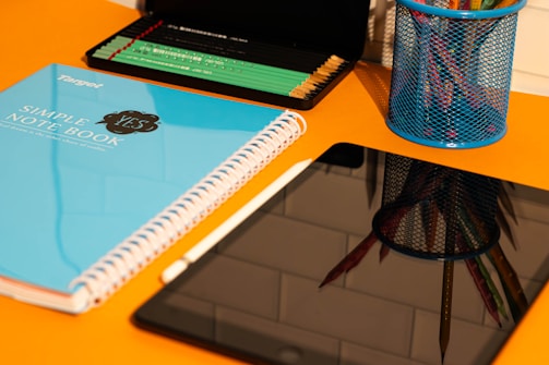 A desk with a laptop, notebook, and a cup of pencils