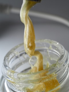 A jar filled with liquid and a spoon with a liquid pouring out of it