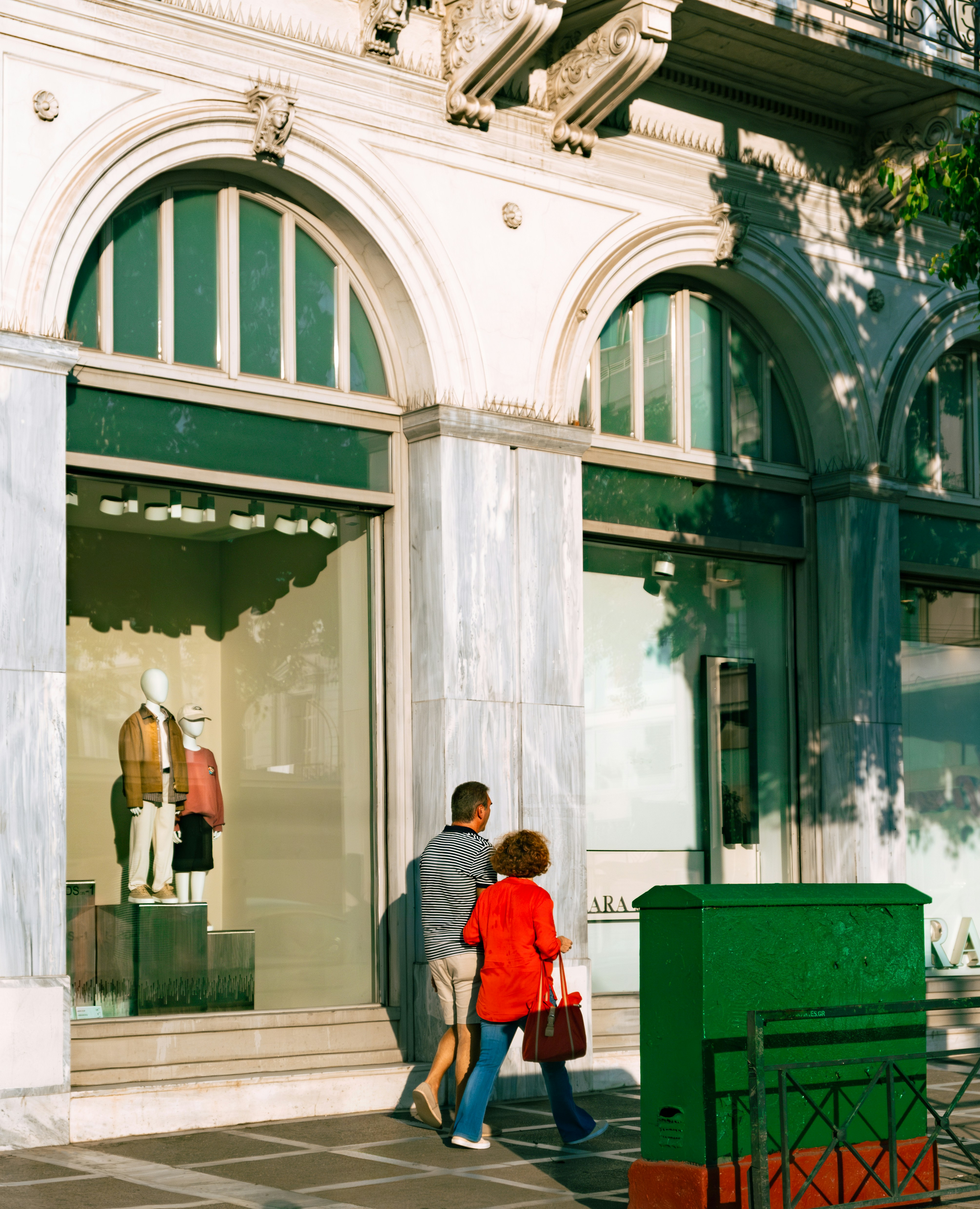 A man and a woman walking past a store front