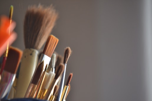 A cup filled with lots of different colored brushes