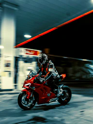 A man riding a red motorcycle down a street