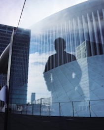 A reflection of a man holding a surfboard in front of a building