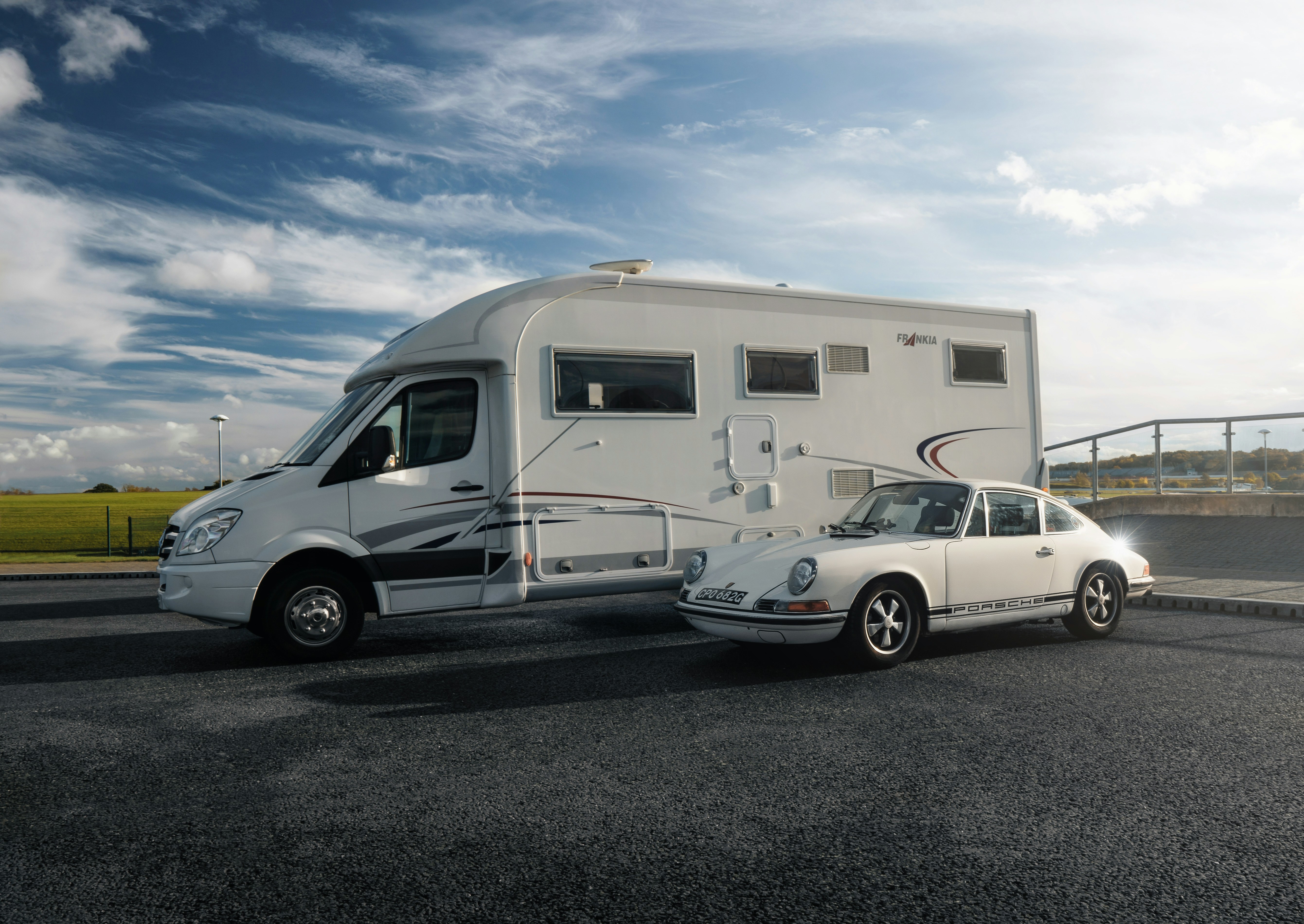 A white car is parked next to a trailer