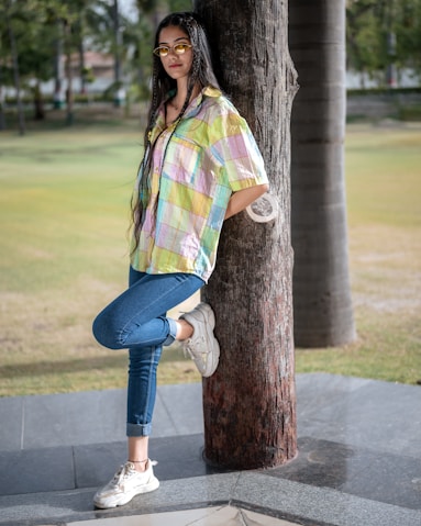 A woman leaning against a tree in a park