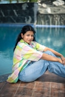 A woman sitting on the ground next to a pool