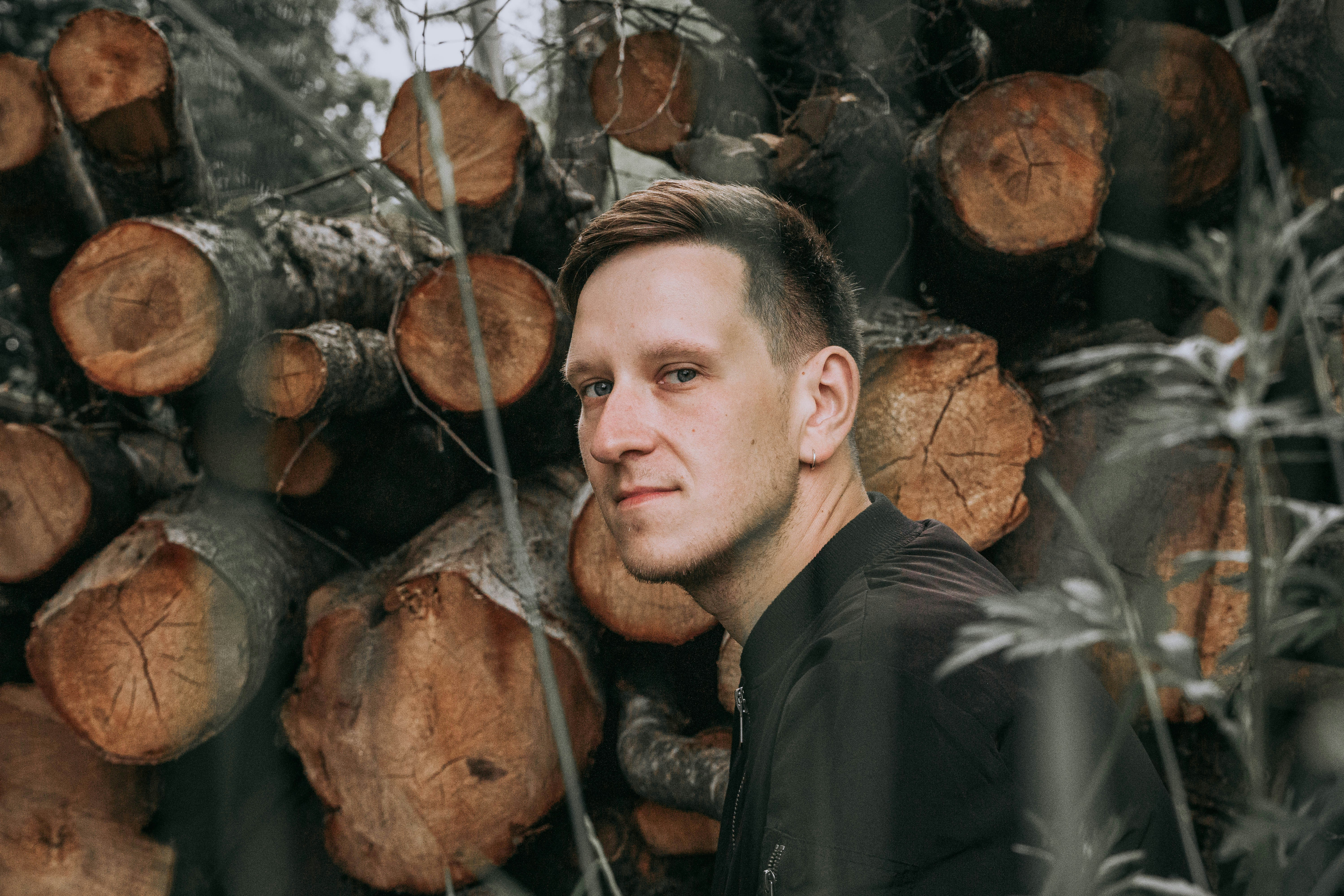 A man standing in front of a pile of logs