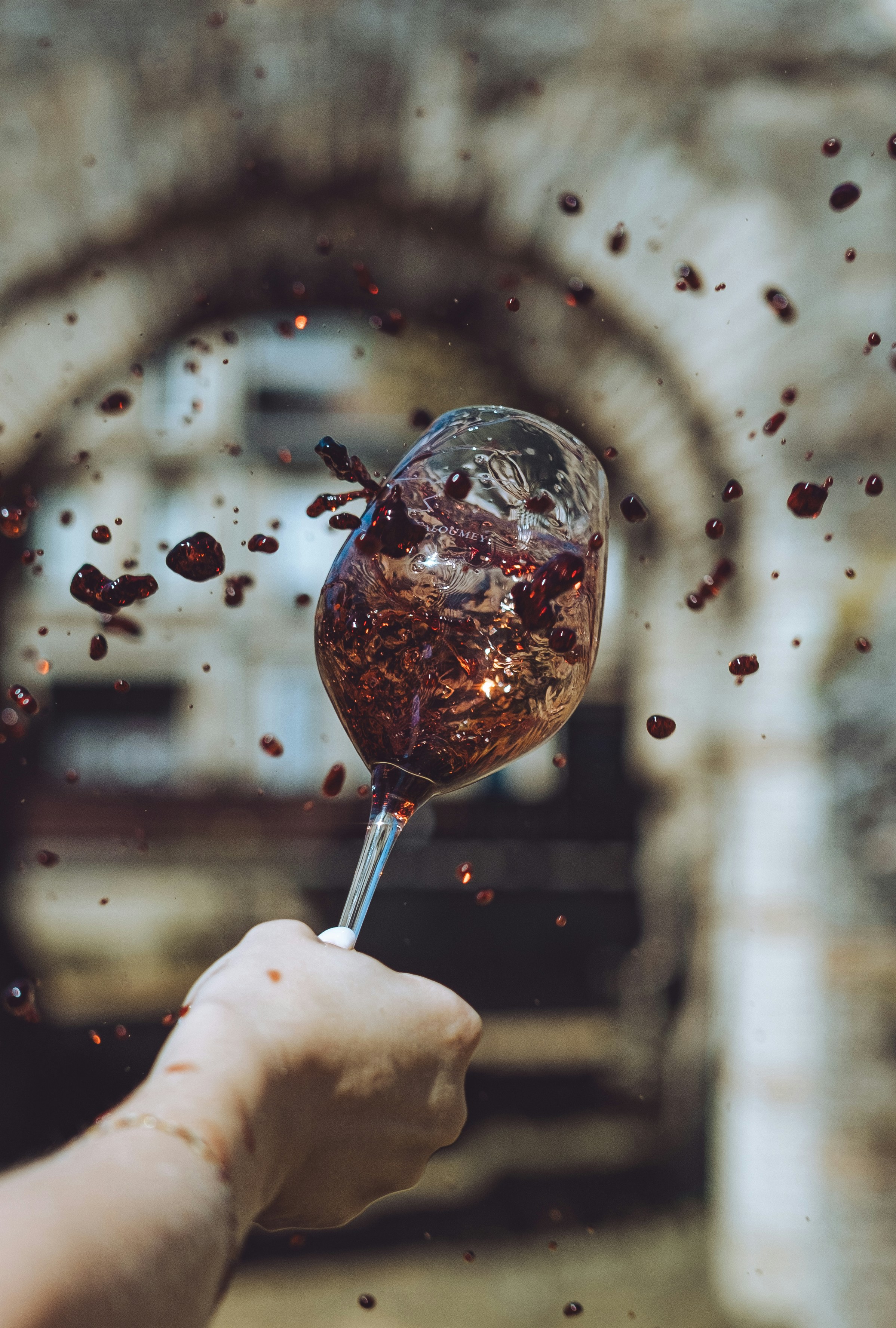 A hand holding a wine glass with red wine coming out of it