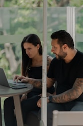 A man and a woman sitting at a table with a laptop