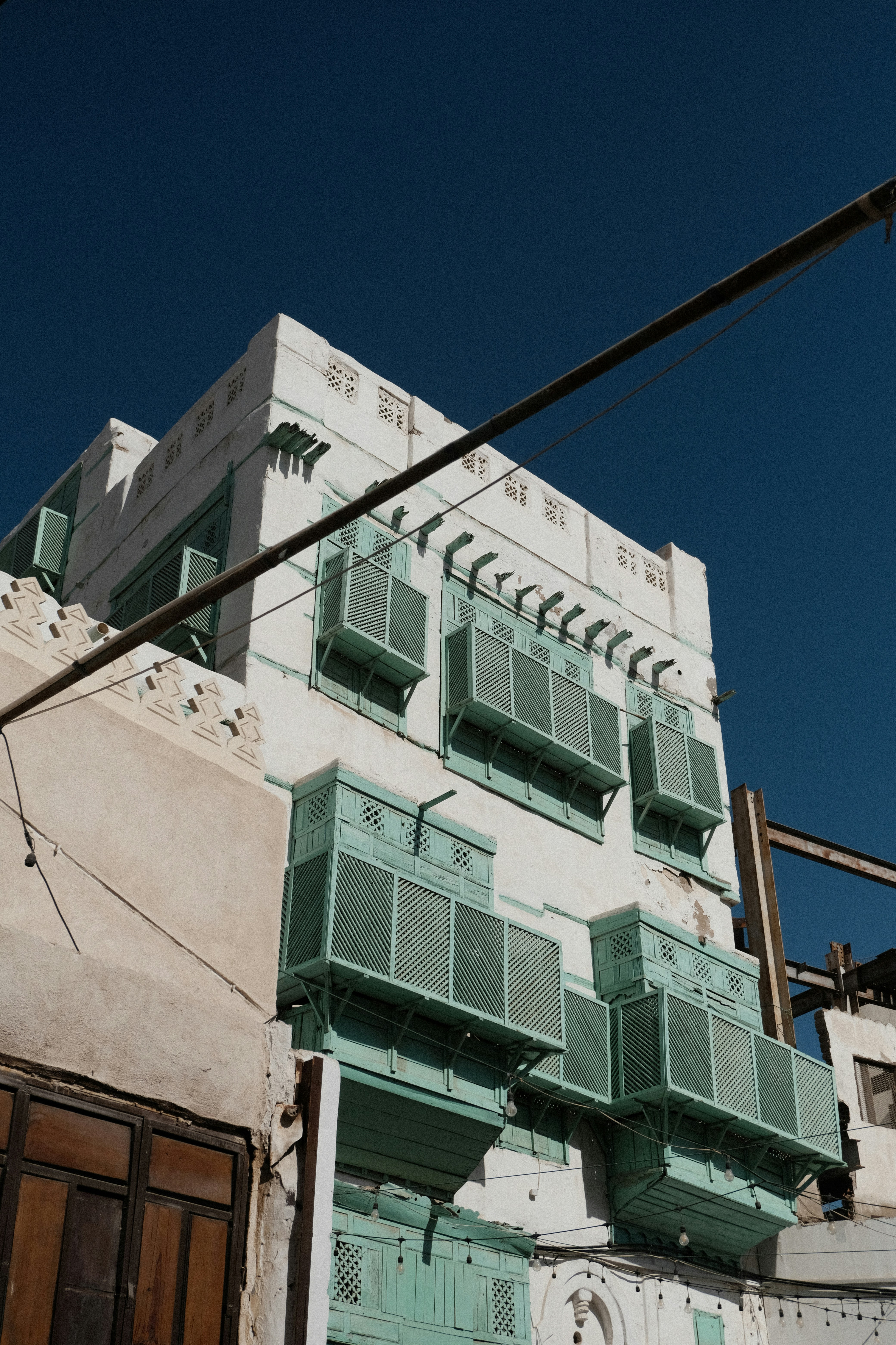 A tall white building with green shutters and a street light