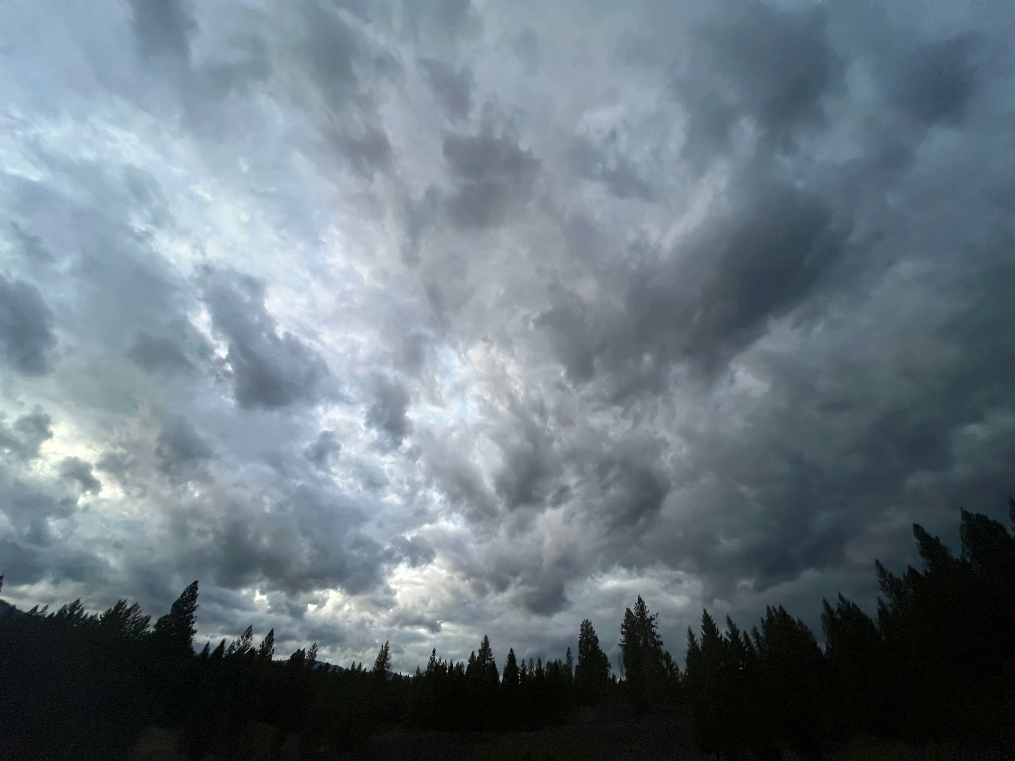 Storm clouds gathering over a forest landscape with dark dramatic sky
