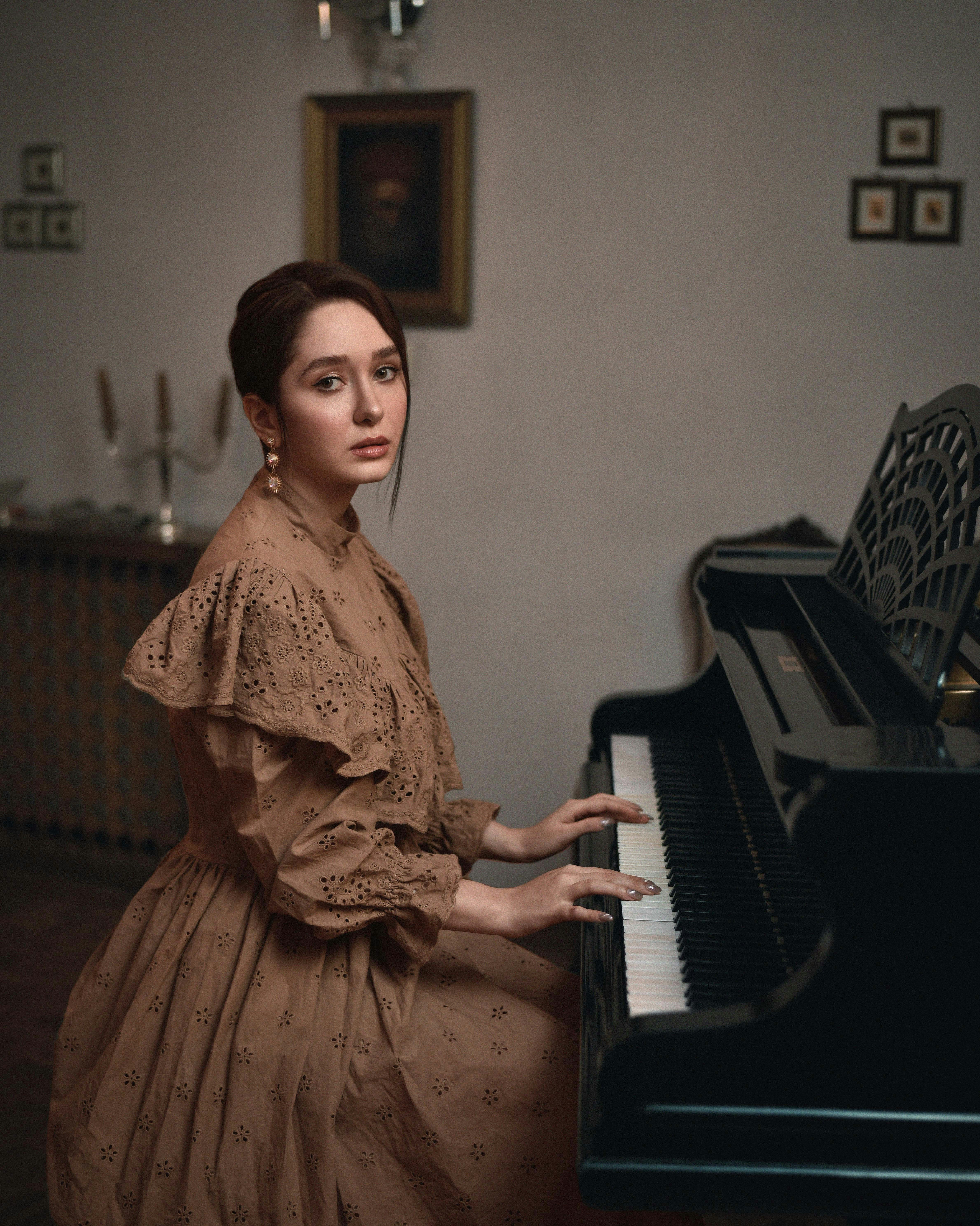 A woman in a brown dress sitting at a piano