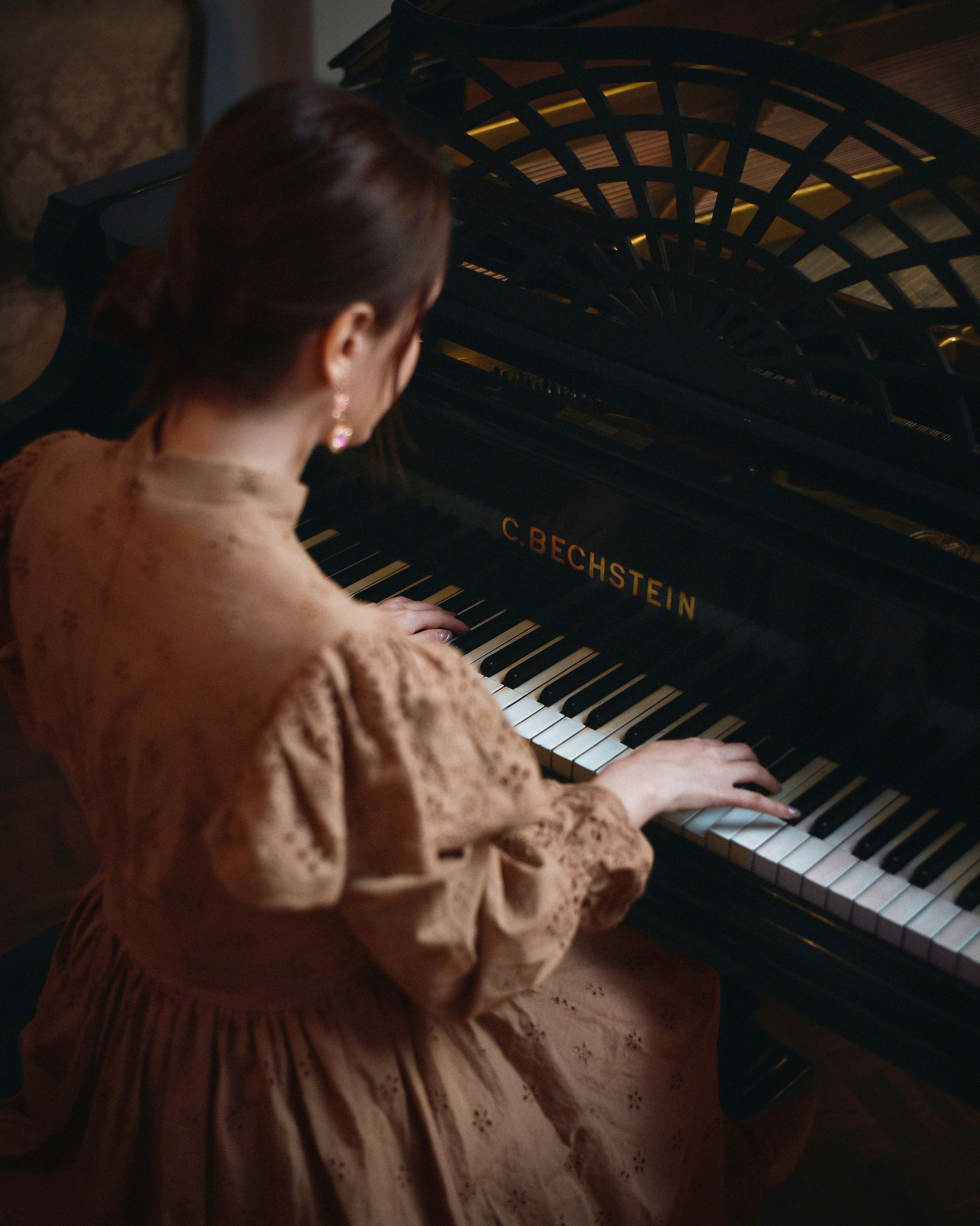 A woman in a brown dress playing a piano