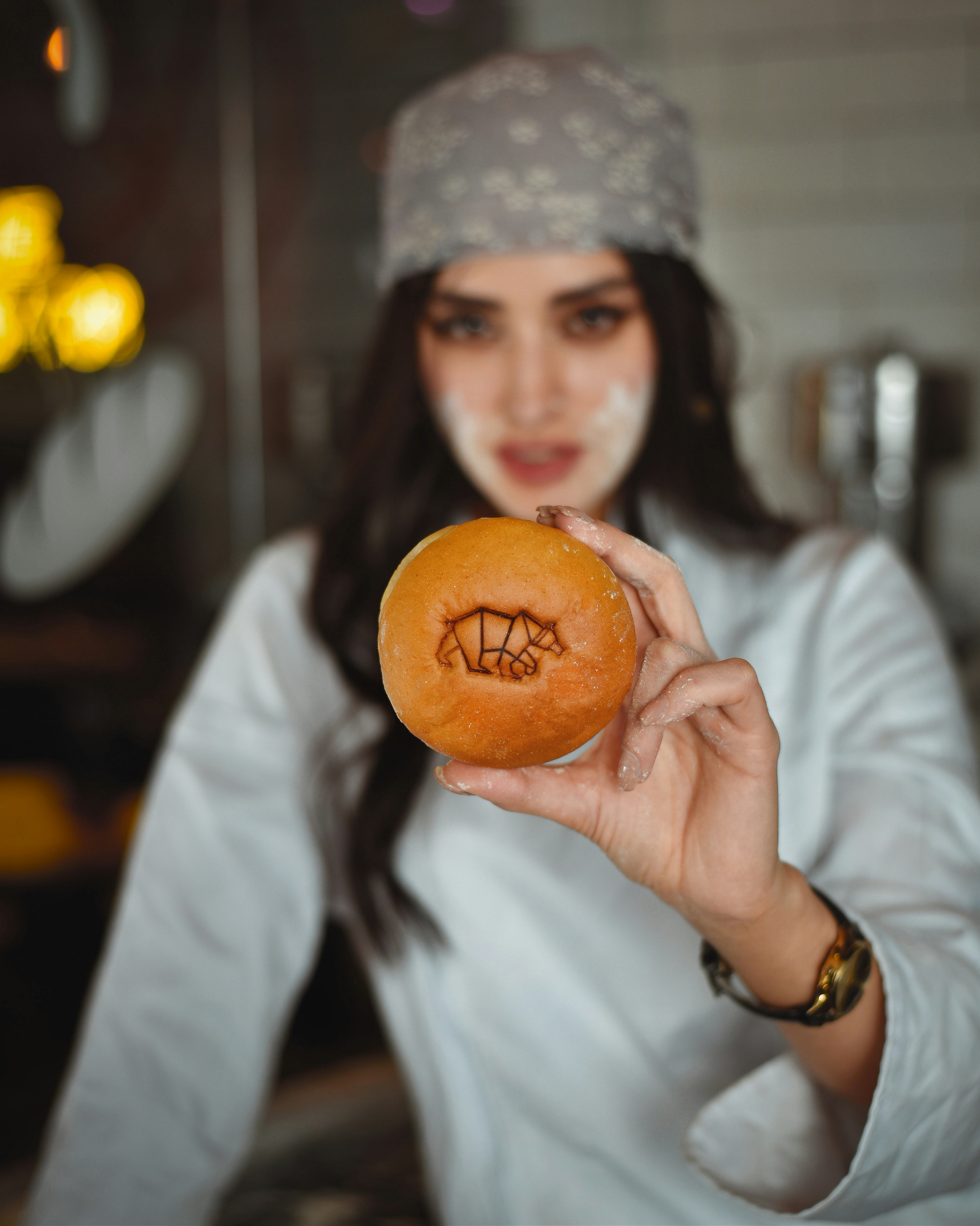 Nour holding up a golden filled doughnut with a sugar pattern on top