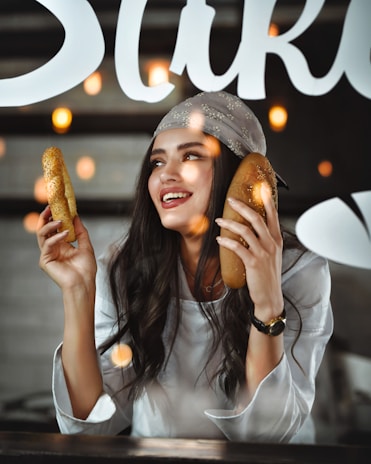 A woman holding two hot dogs in front of her face