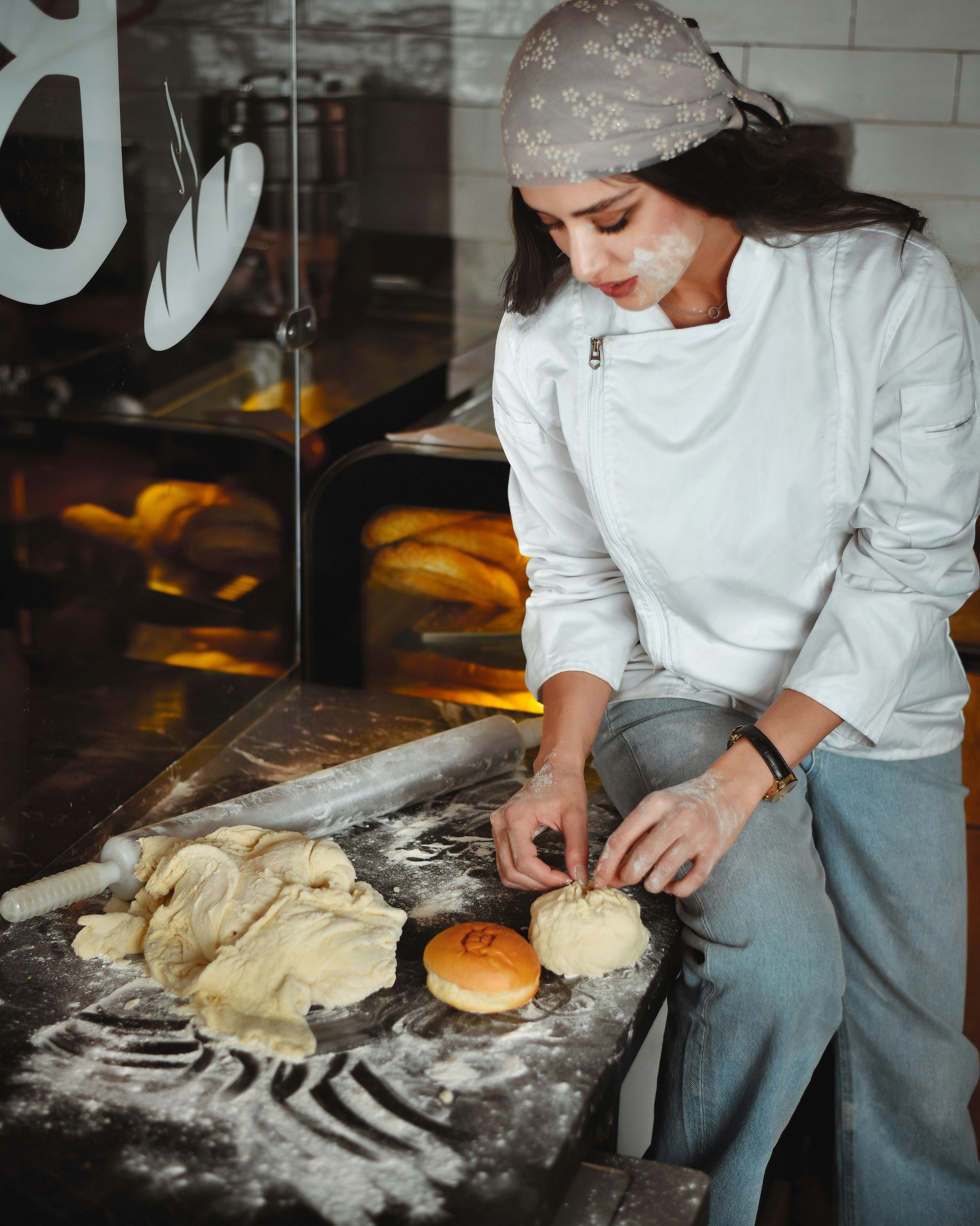 Nour shaping soft dough into buns on a floured counter
