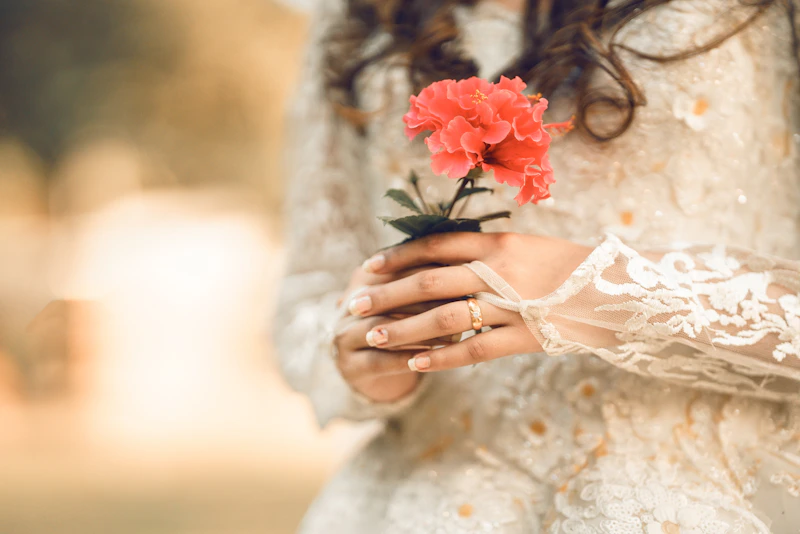 elegant woman in white dress holding a red flower
