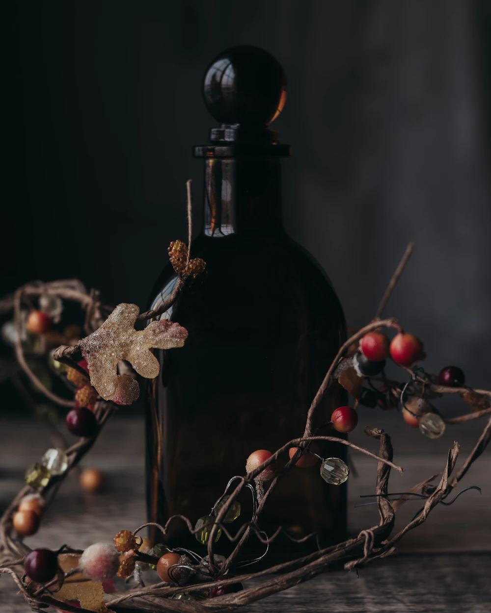 Amber perfume bottle in a dark still life with autumn berries