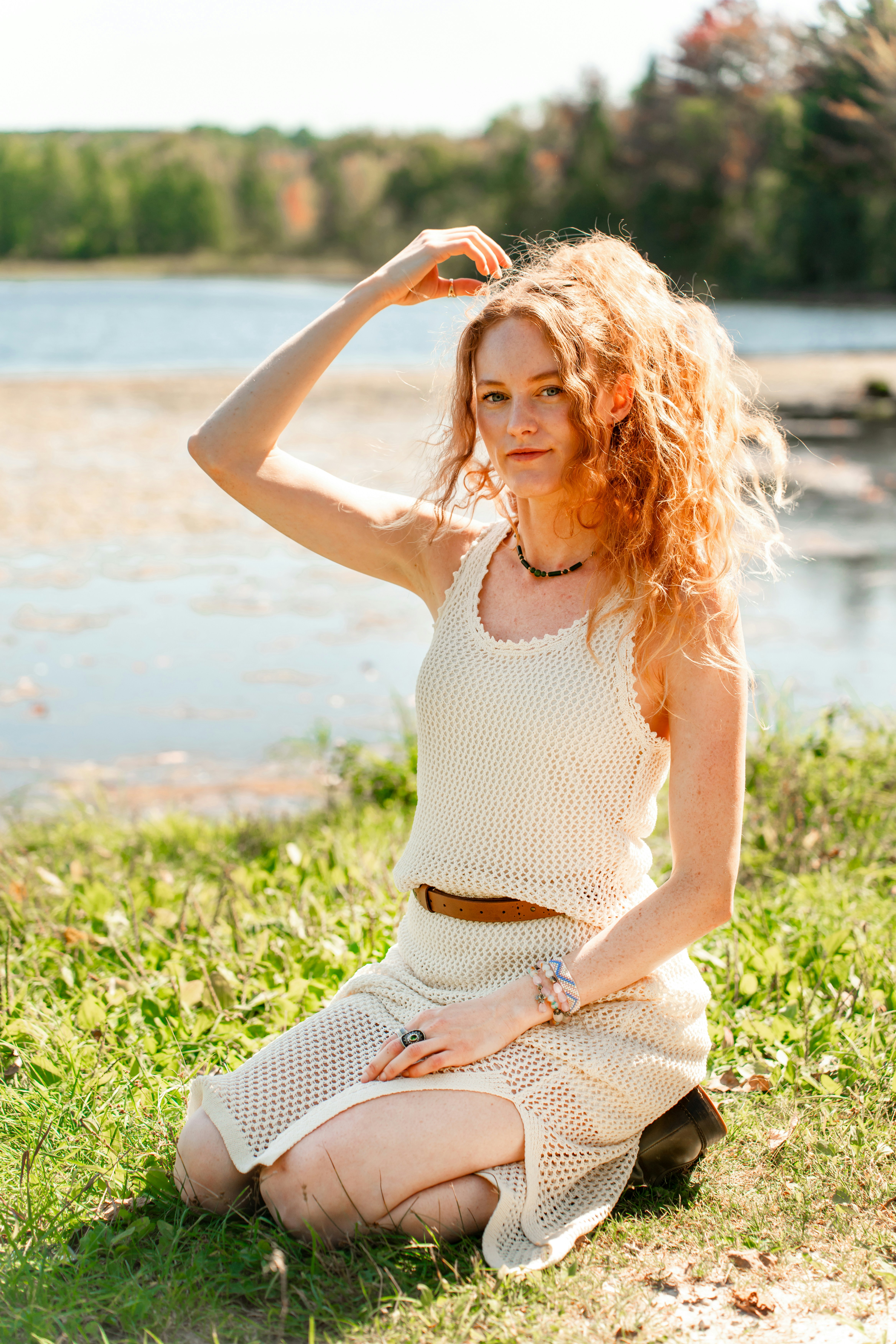 A woman sitting on the grass near a body of water