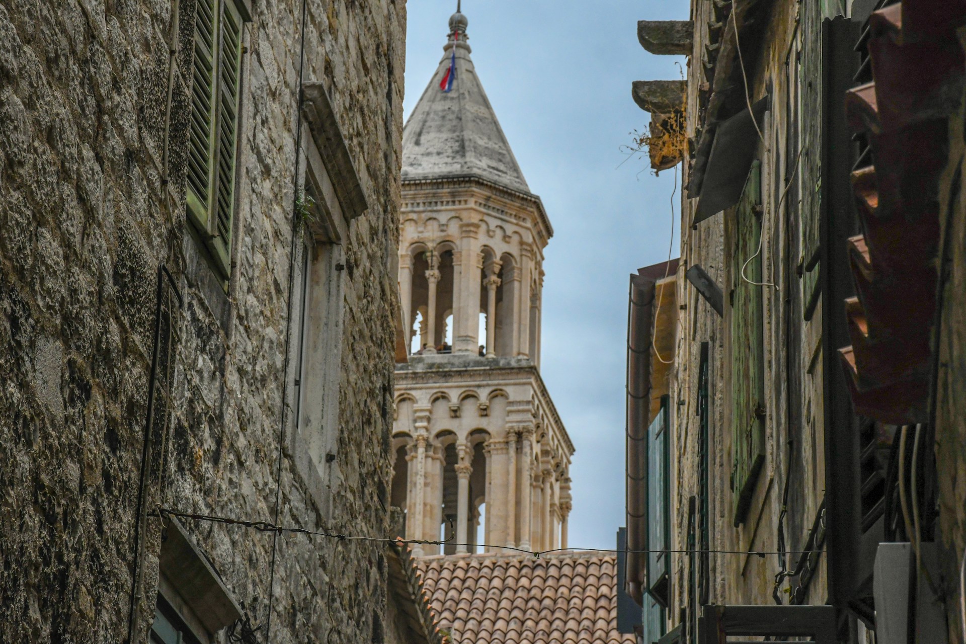 A narrow street with a church steeple in the background