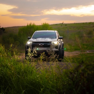 A silver truck driving down a dirt road