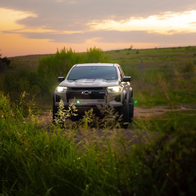 A silver truck driving down a dirt road