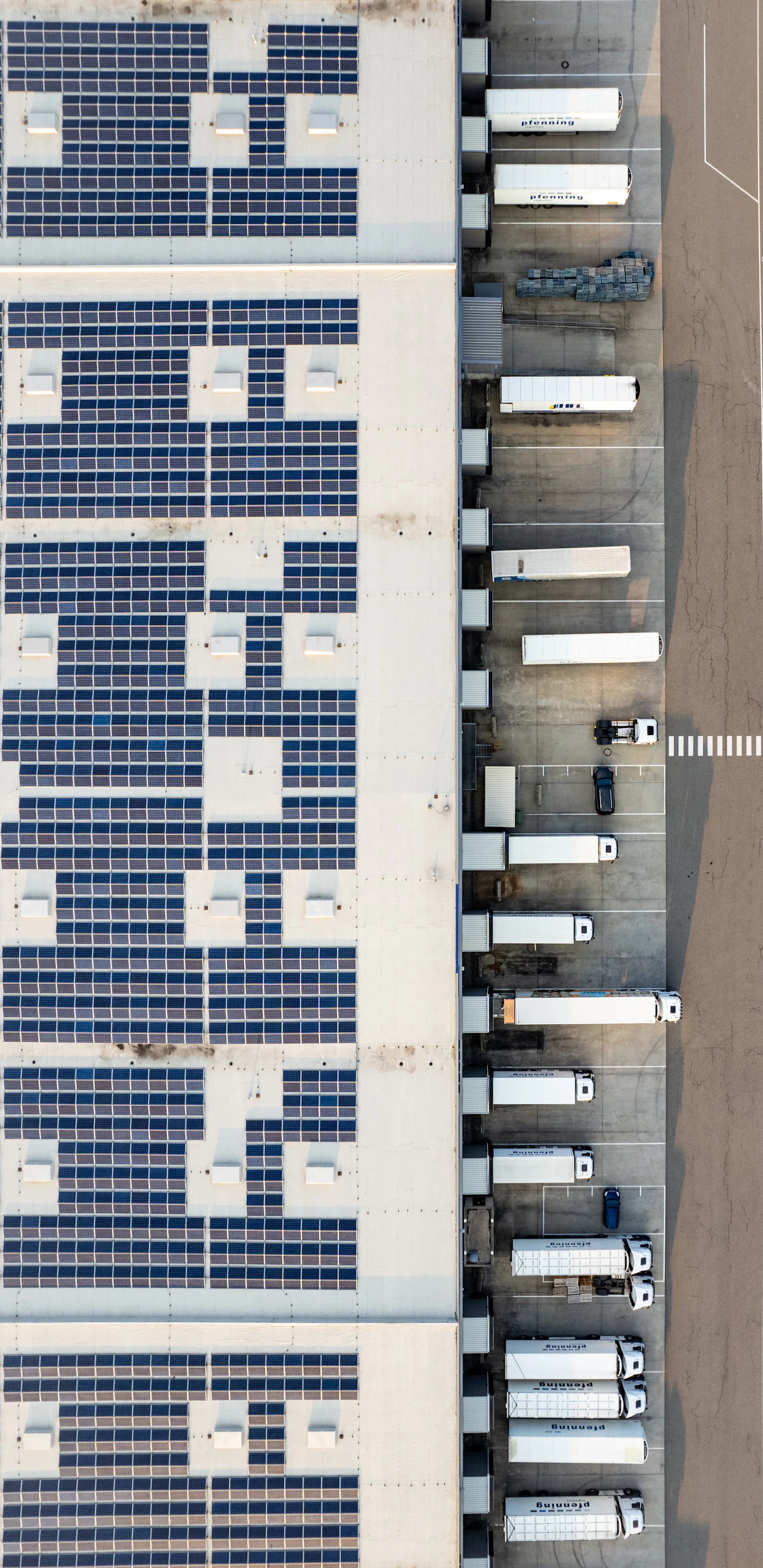 Aerial view of an industrial warehouse facility with extensive rooftop solar PV array