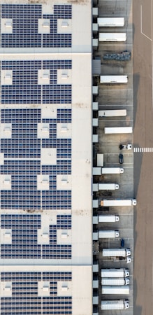 An aerial view of a large industrial building with a rooftop covered in solar panels, showing the scale of modern distribution centers