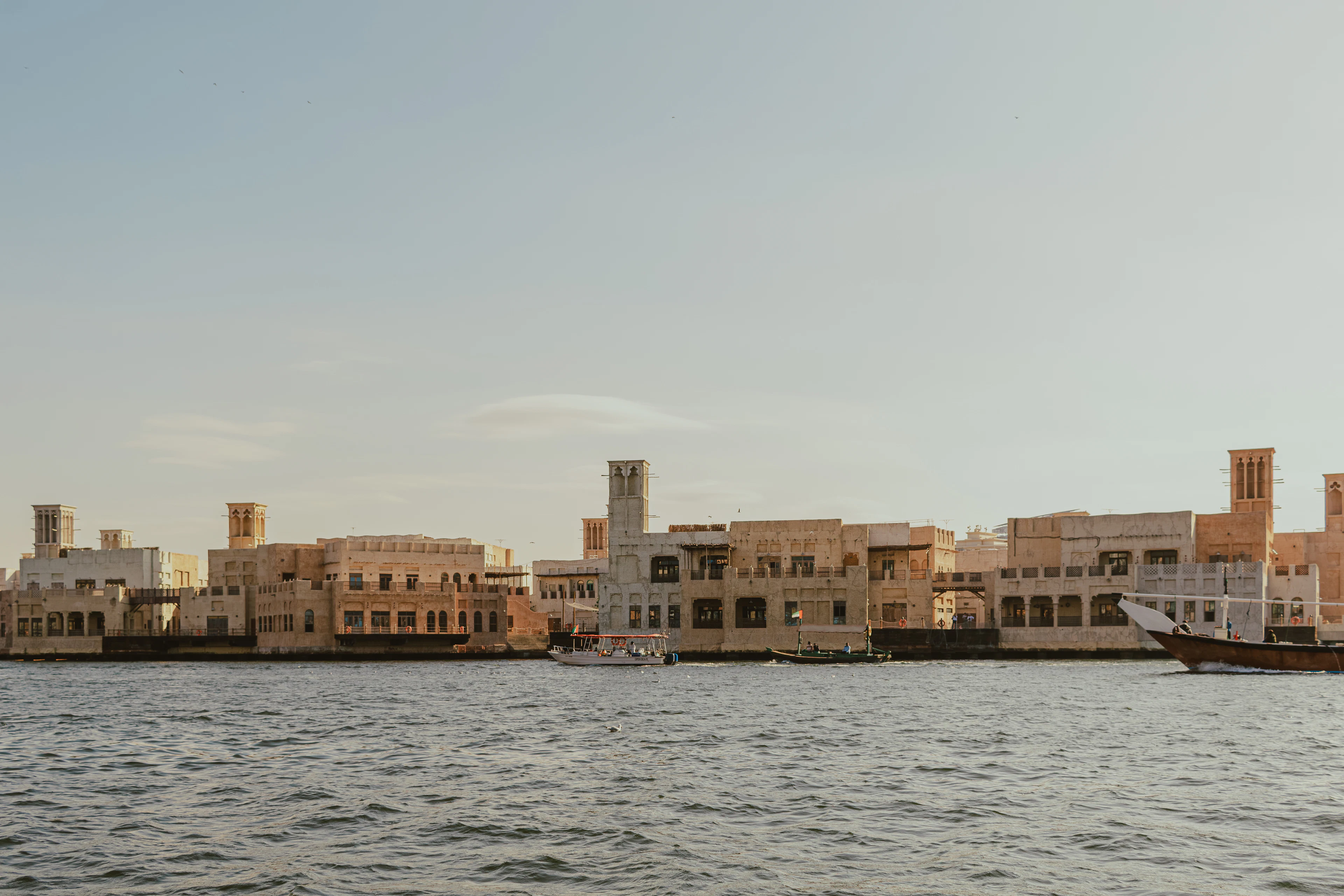 Traditional wind towers and sand-coloured buildings along the Dubai Creek waterfront