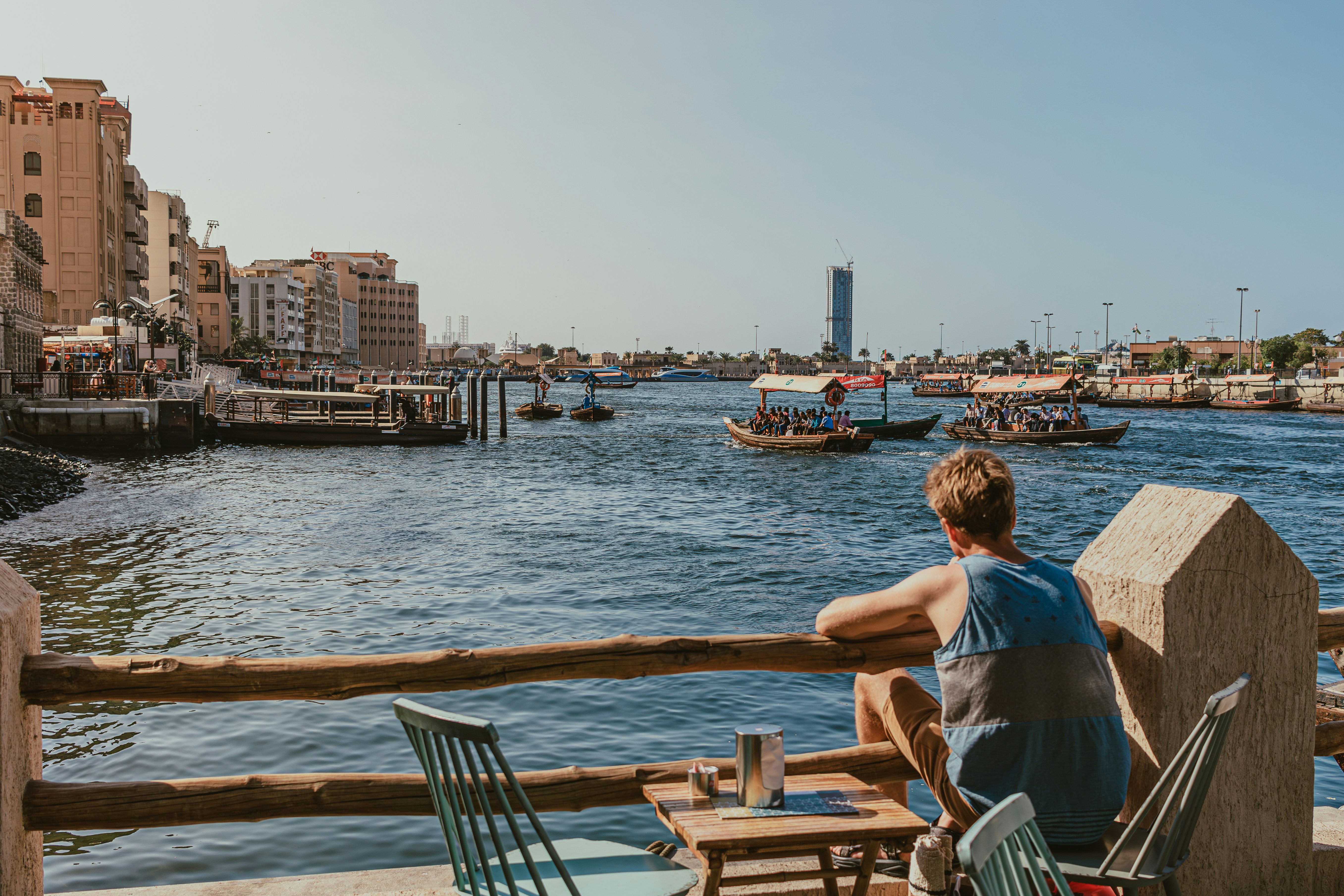 Man relaxing by Dubai Creek watching abras sail across the waterby Kate Trysh