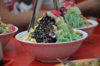 A table topped with three bowls filled with food