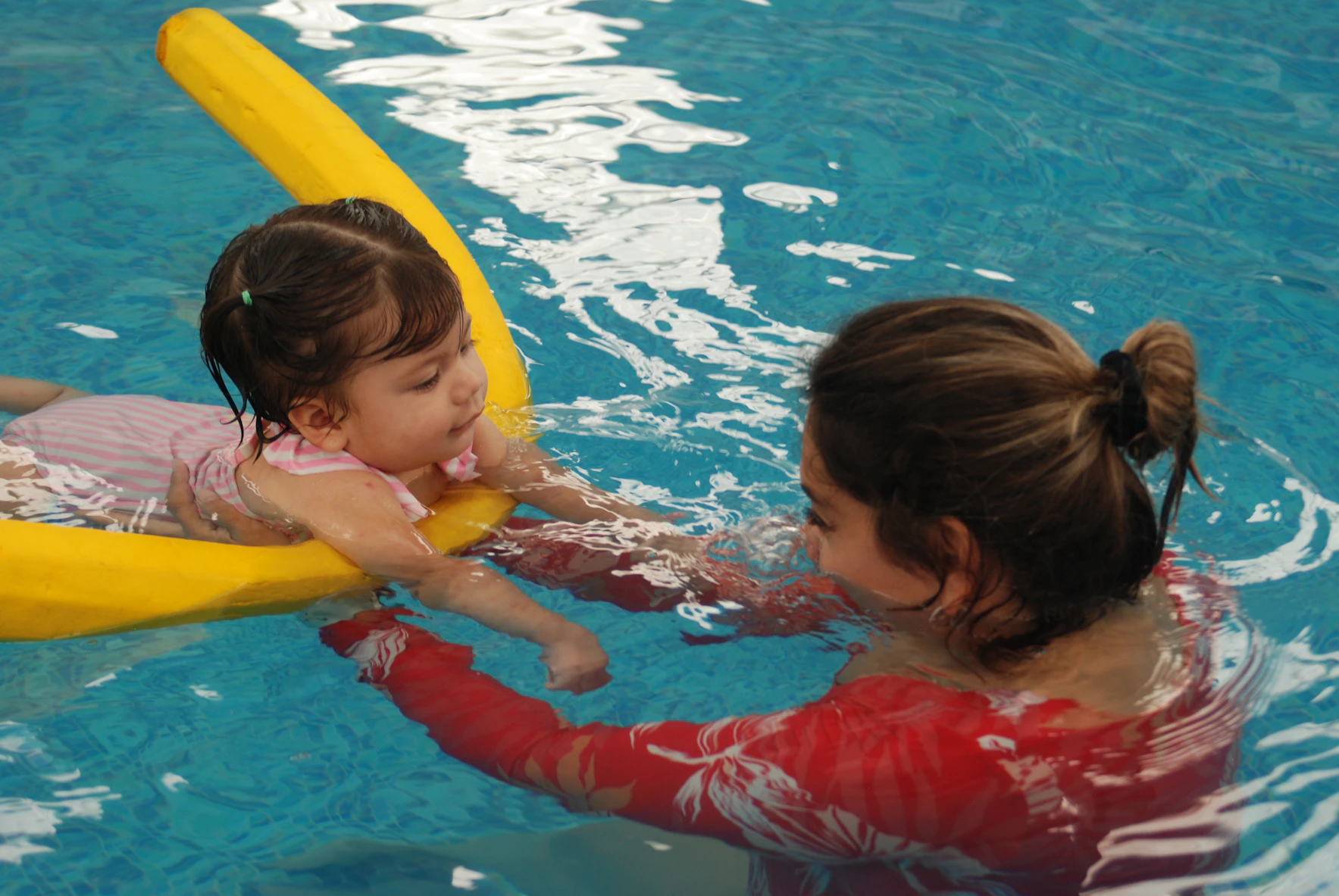 Swim instructor holding a toddler in the pool