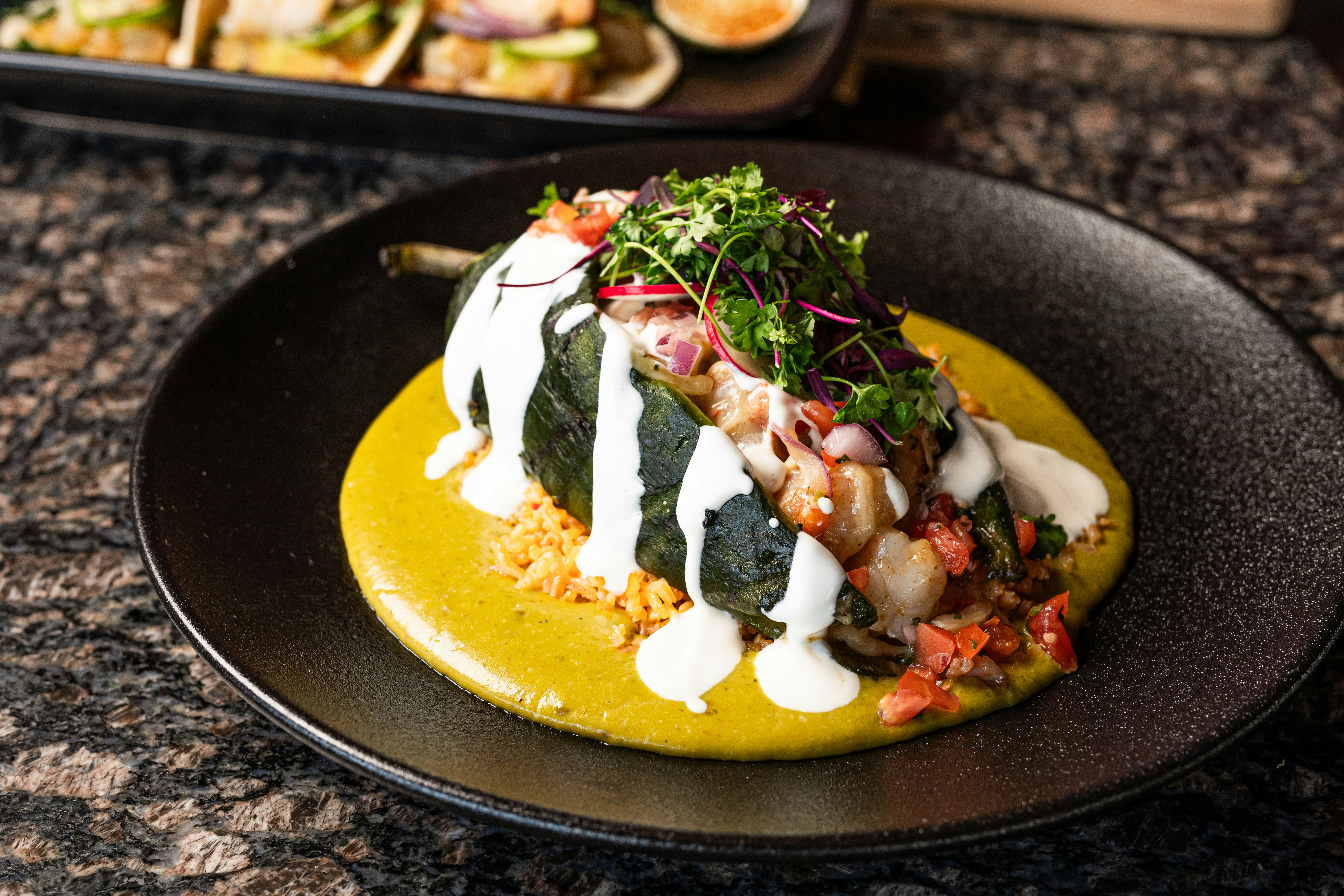 A plate of food on a table next to a tray of food