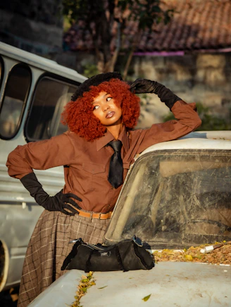 A woman with red hair standing next to a car