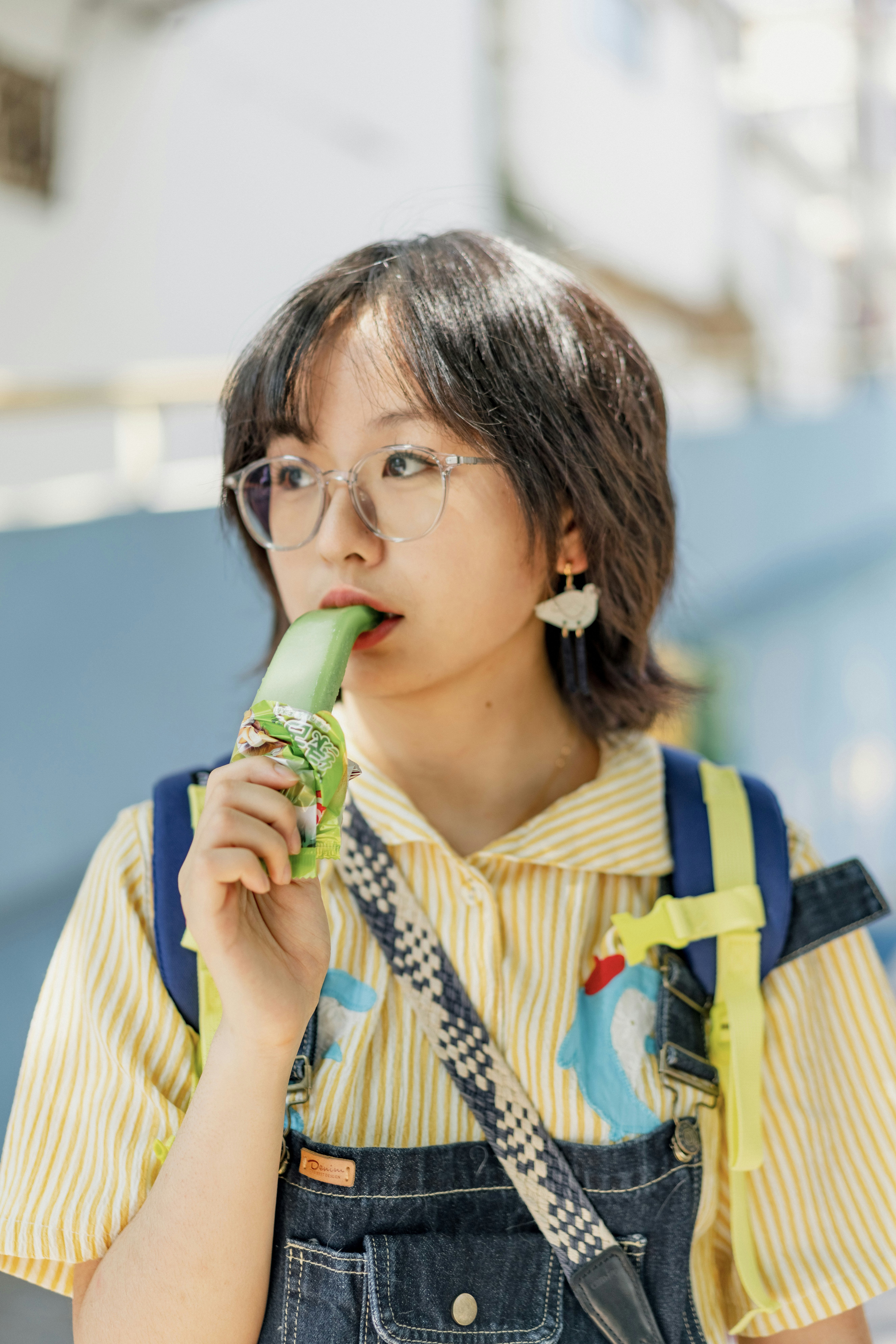 A girl in overalls eating a piece of food