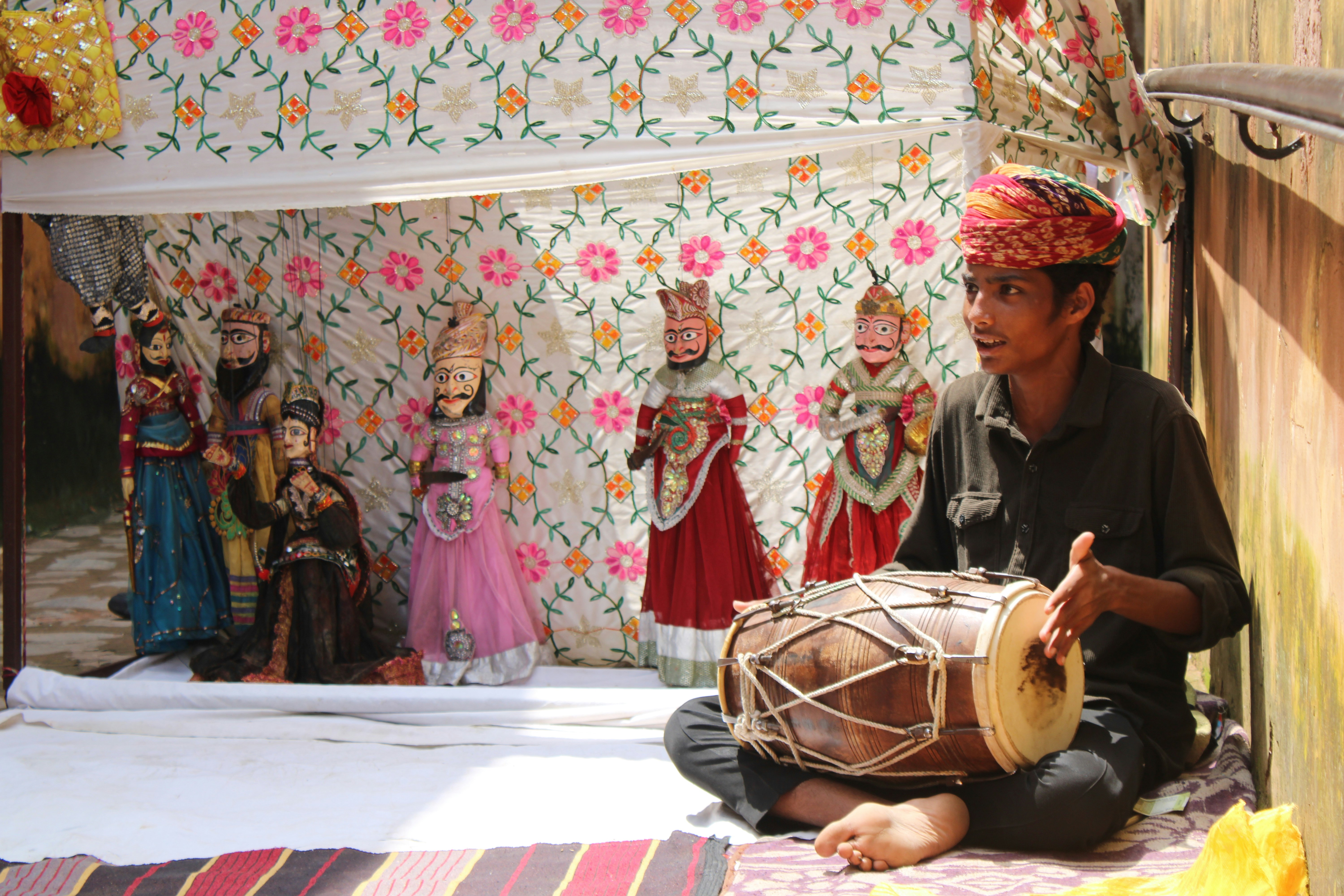 A man sitting on the ground playing a drum