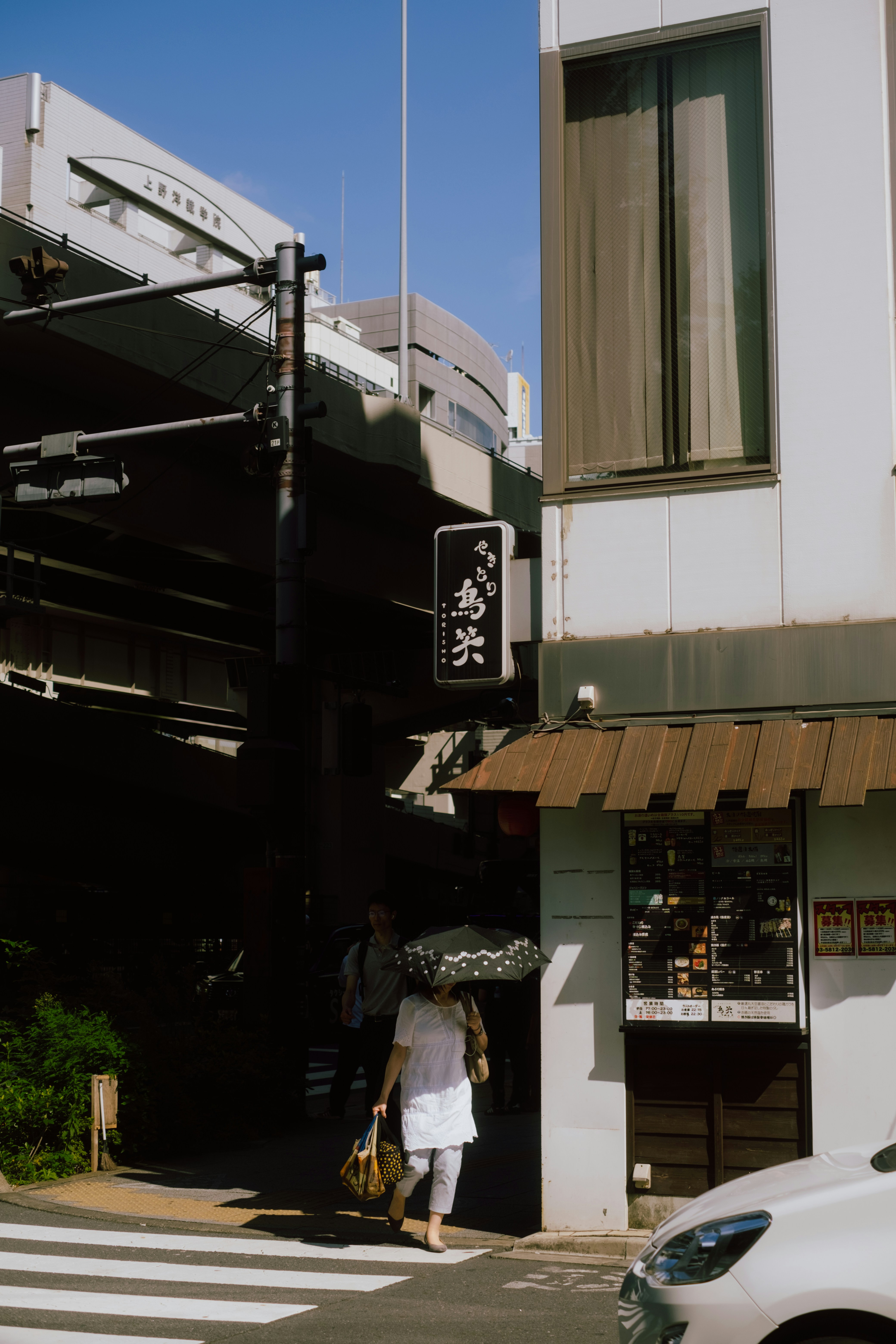 A white car driving down a street next to a tall building photo Free