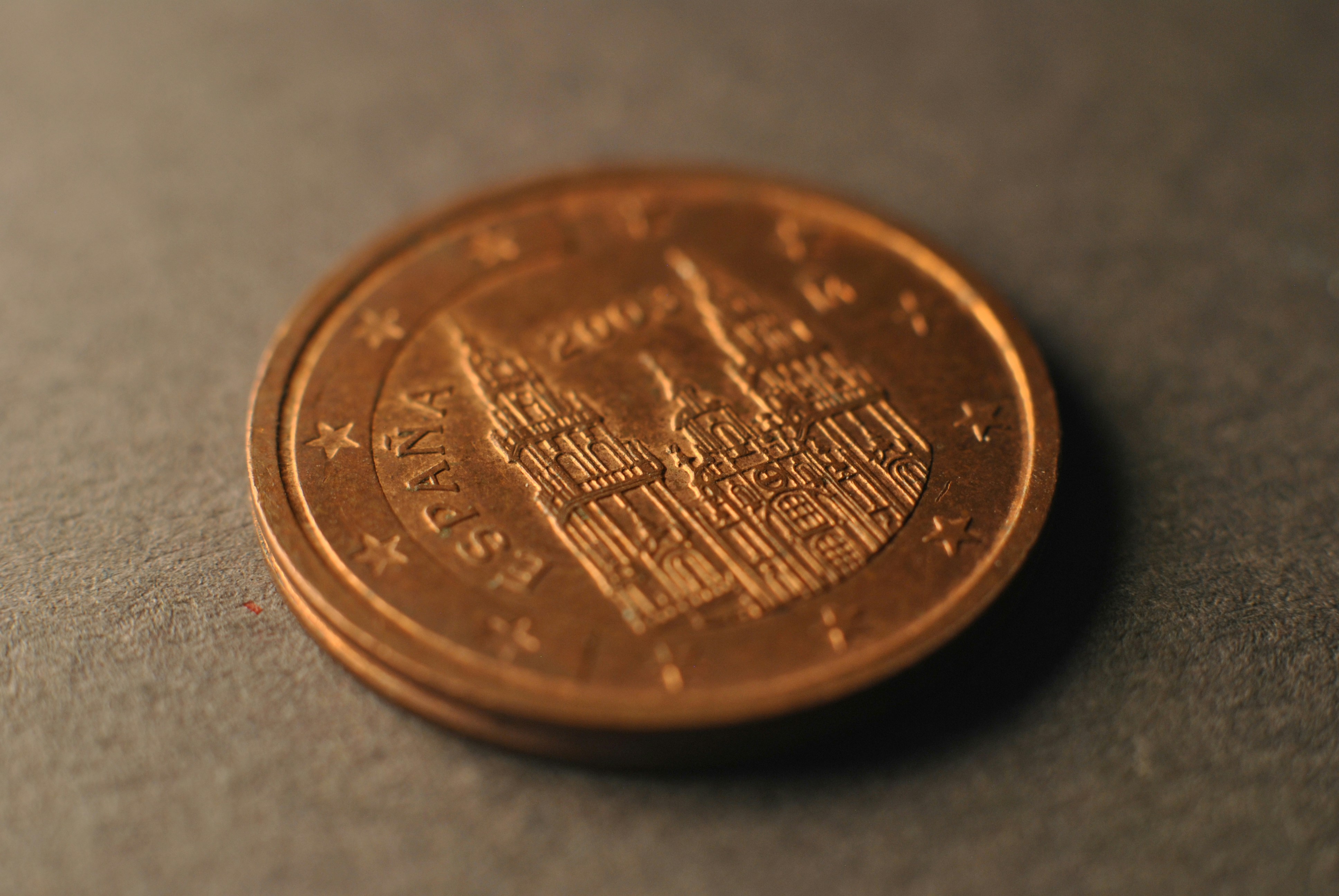 A hand carefully placing a single coin onto a miniature house, symbolizing real estate commission savings.