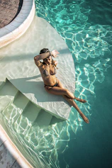 A woman in a bikini sitting on a raft in a pool