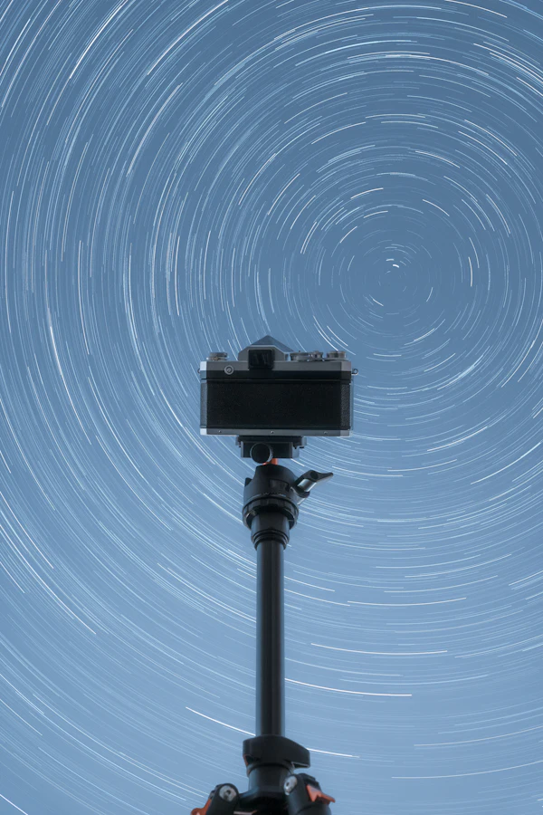 Camera on a tripod pointed at circular star trails during a long night exposure