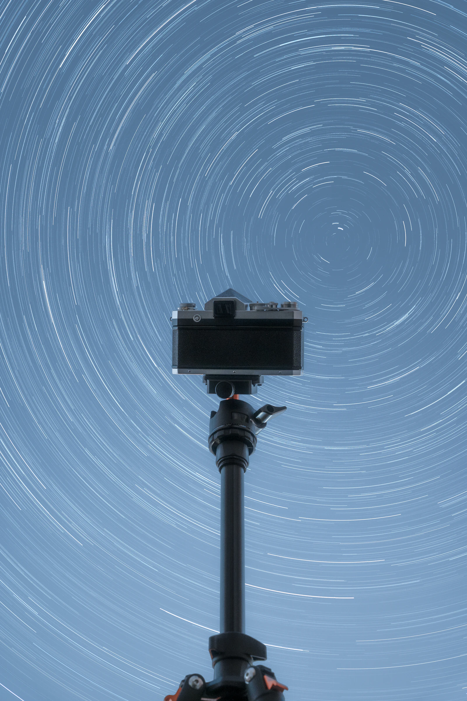 Camera on a tripod pointed at circular star trails during a long night exposure