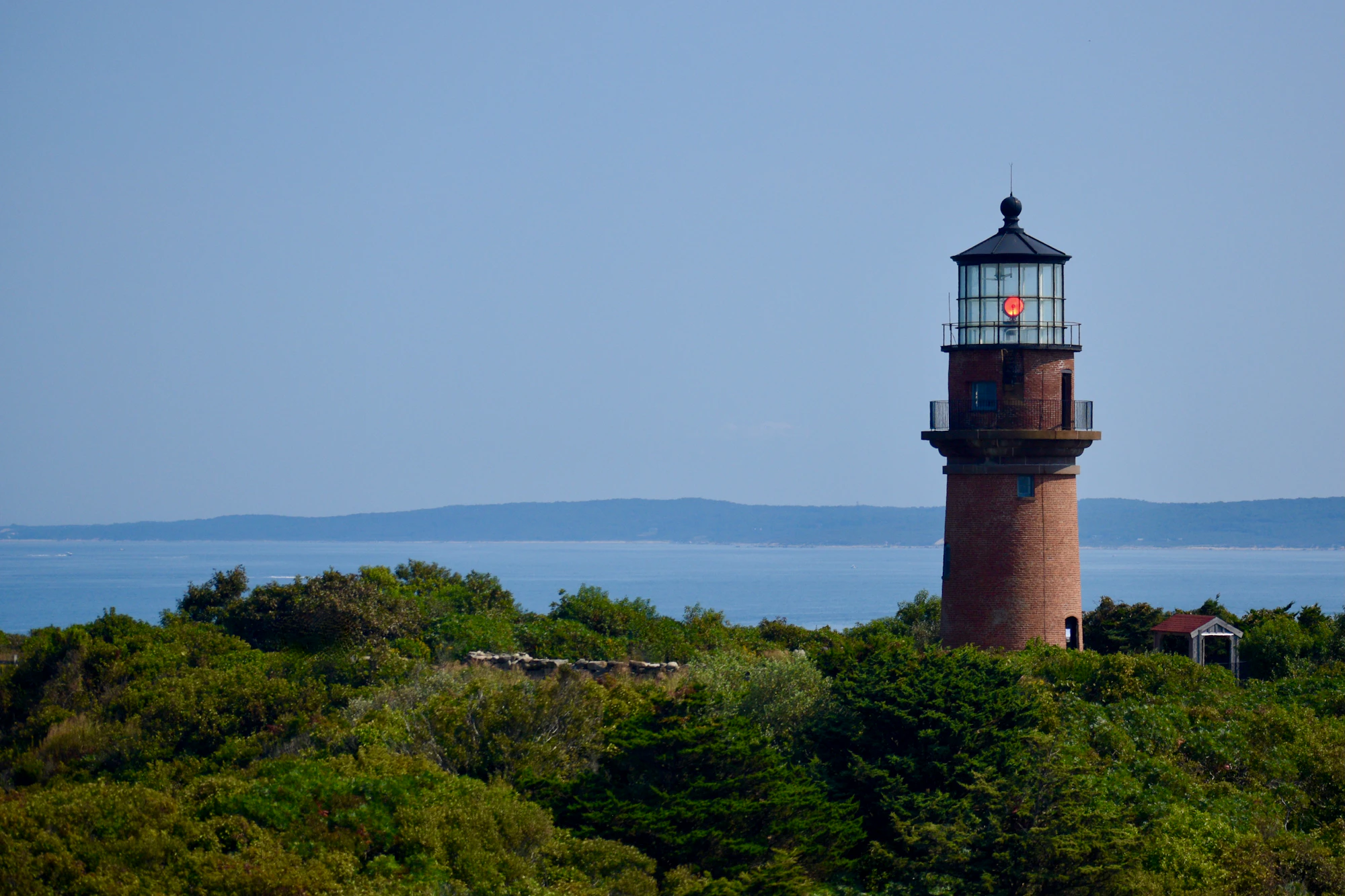 Gay Head Lighthouse is visible above the trees with the blue ocean on the horizon.
