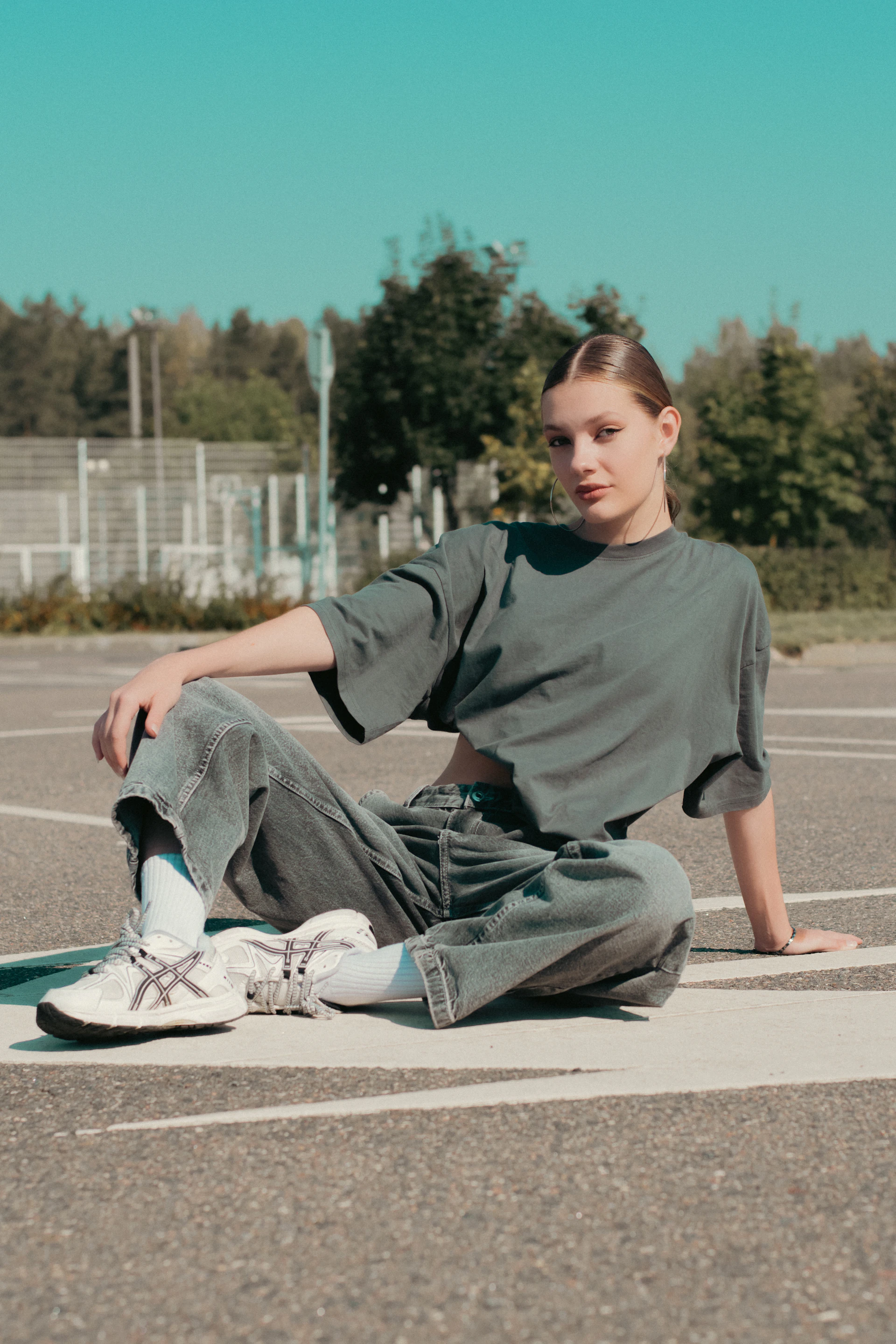 A girl sitting on the ground in a parking lot