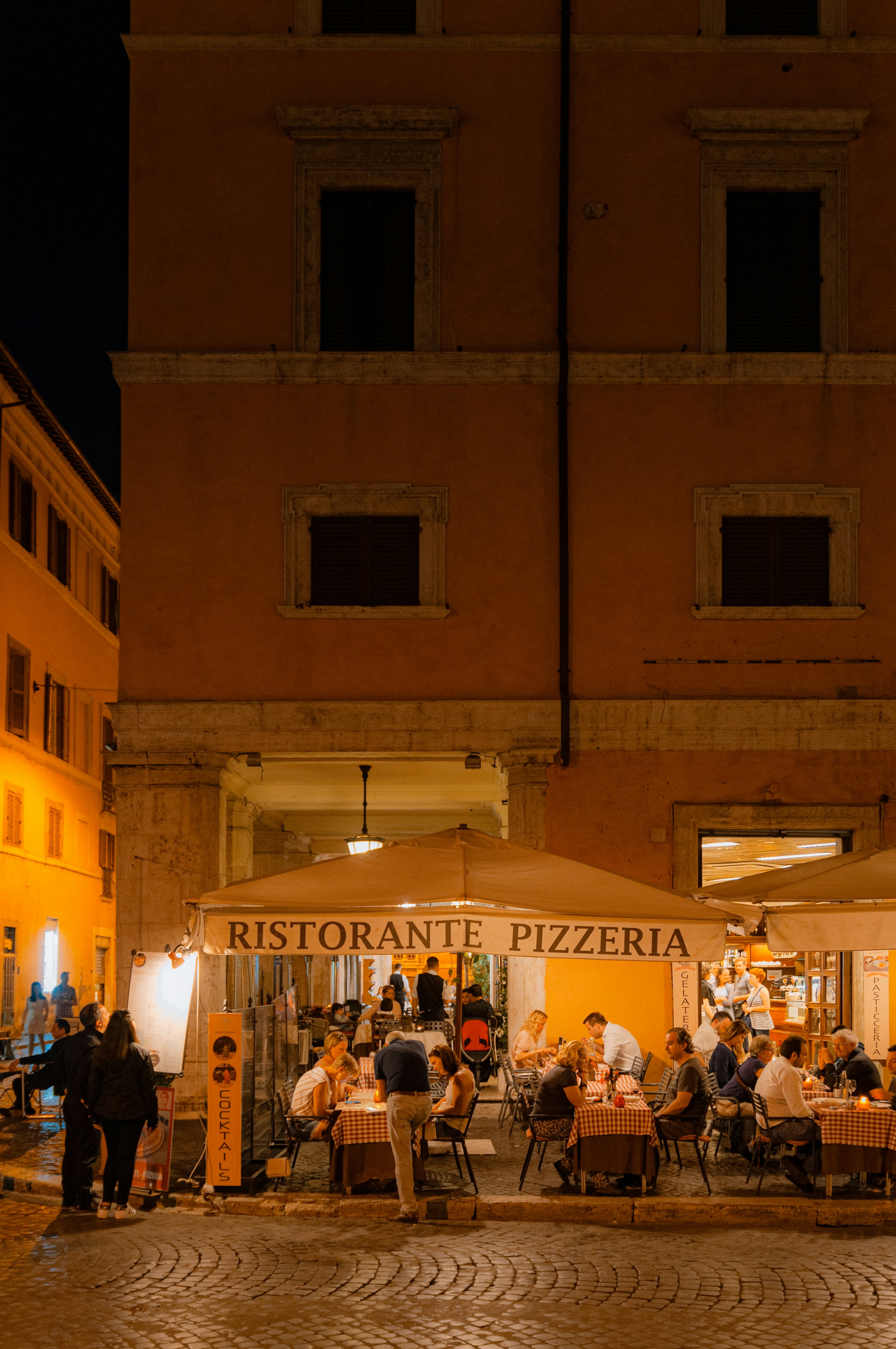 A group of people sitting at tables in front of a building