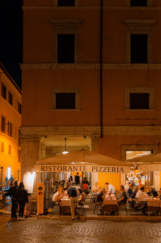 A group of people sitting at tables in front of a building