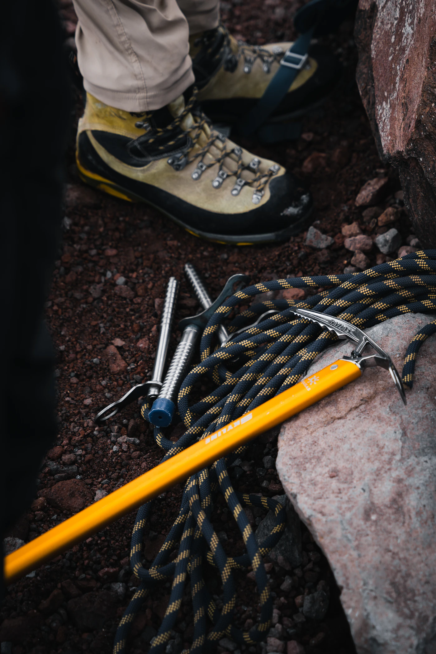 Botas de montaña junto a material técnico de ruta sobre terreno rocoso