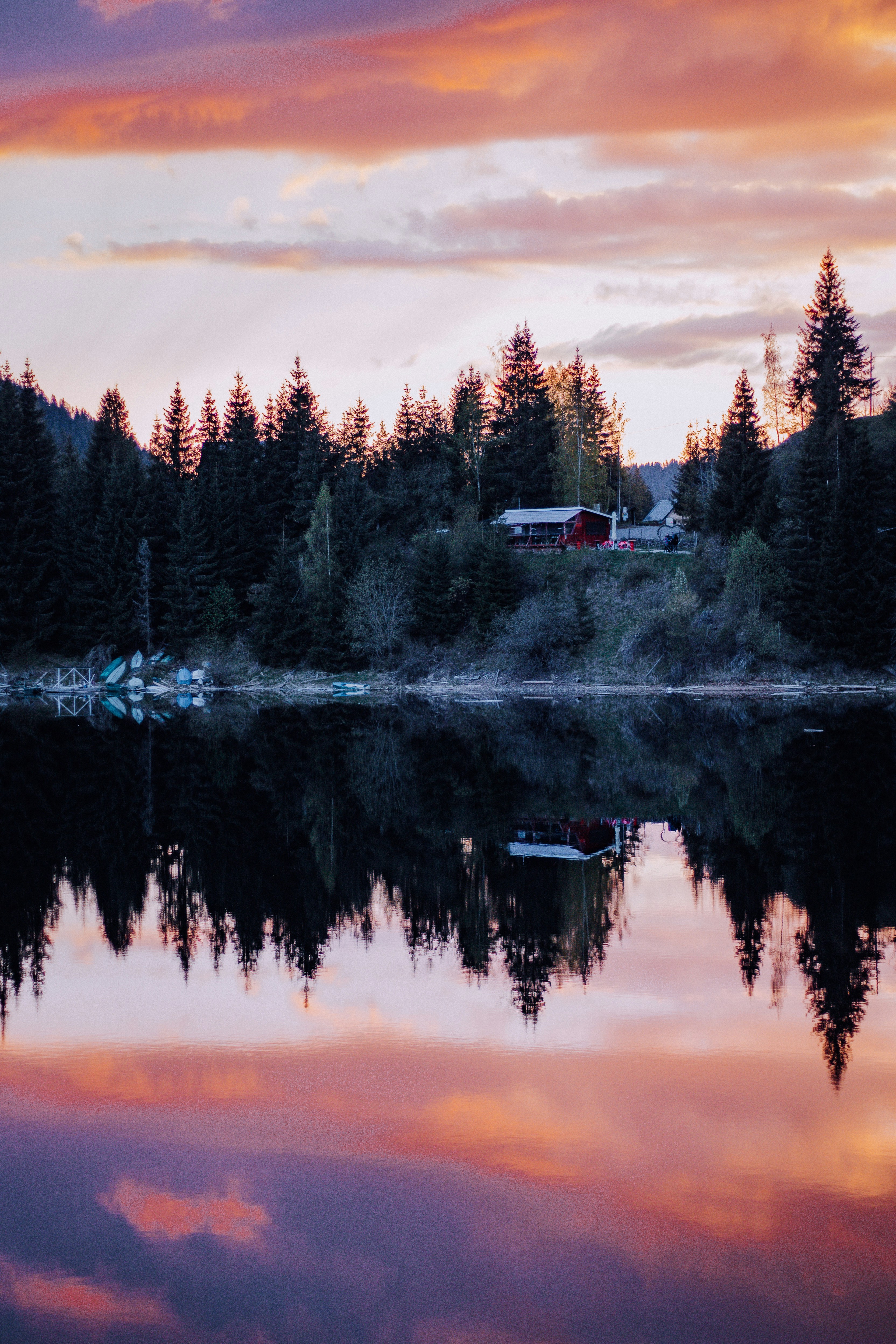Un lago rodeado de árboles con un cielo rojo al fondo
