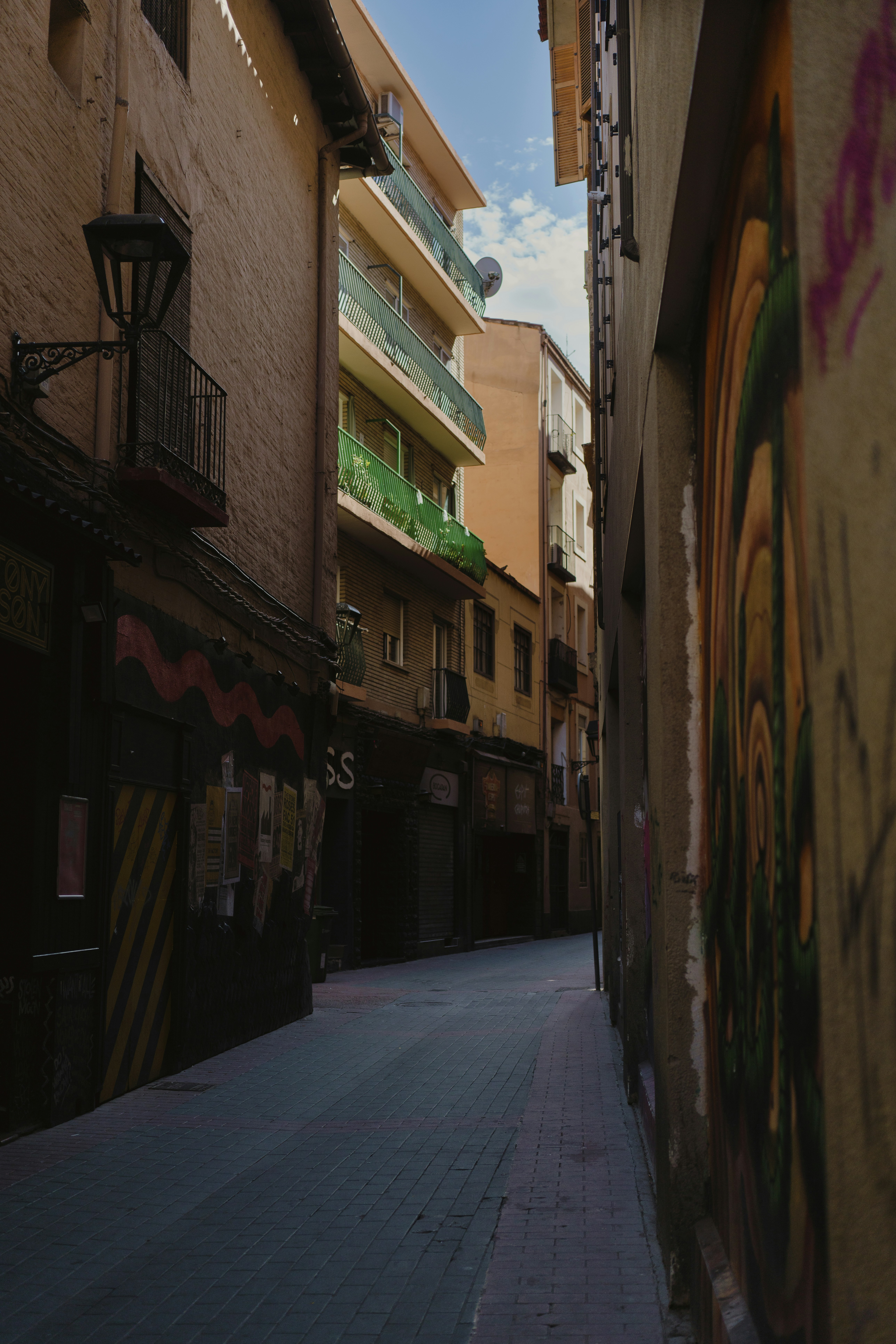 A narrow city street with graffiti on the buildings