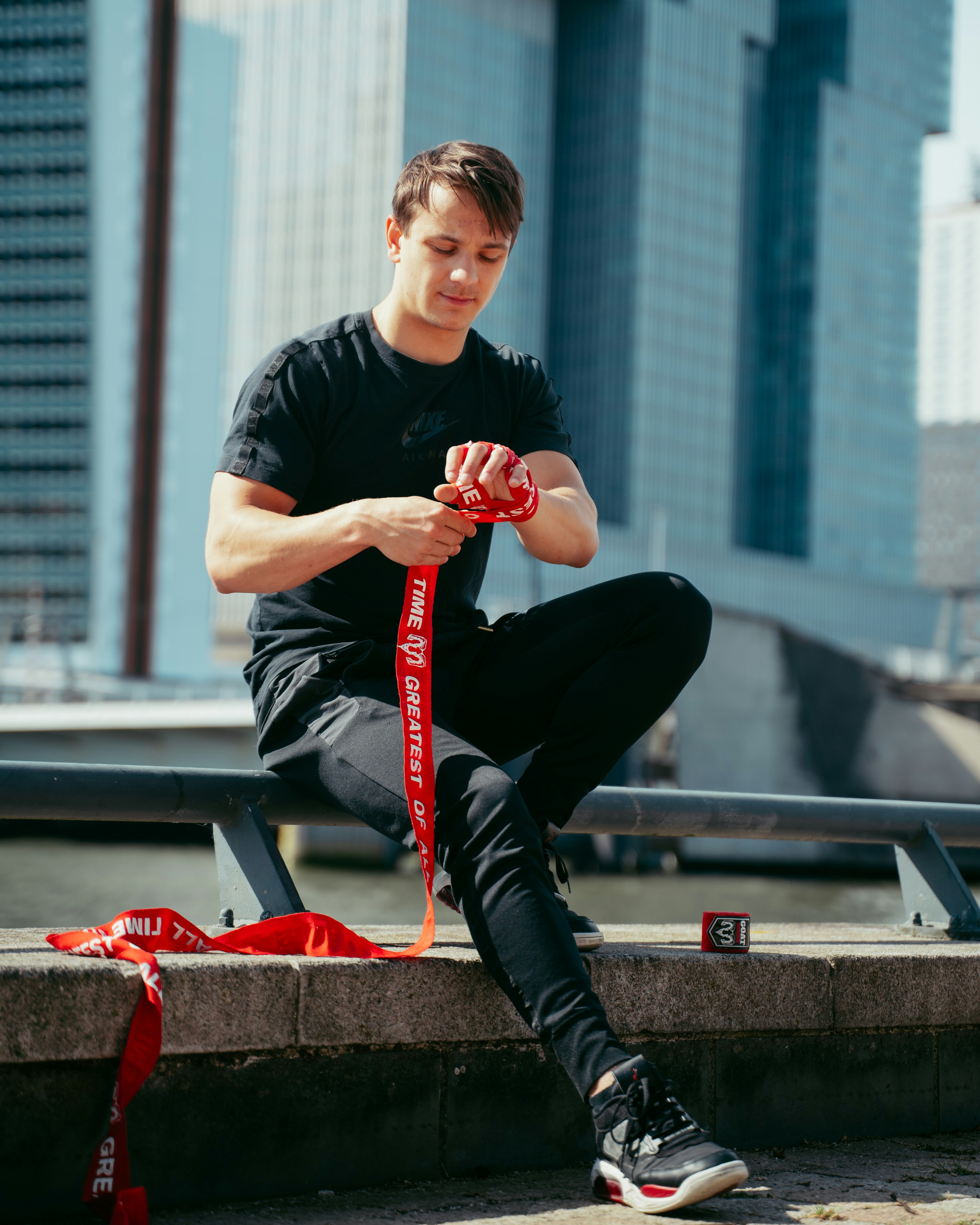 A man sitting on a ledge with a red ribbon around his ankles