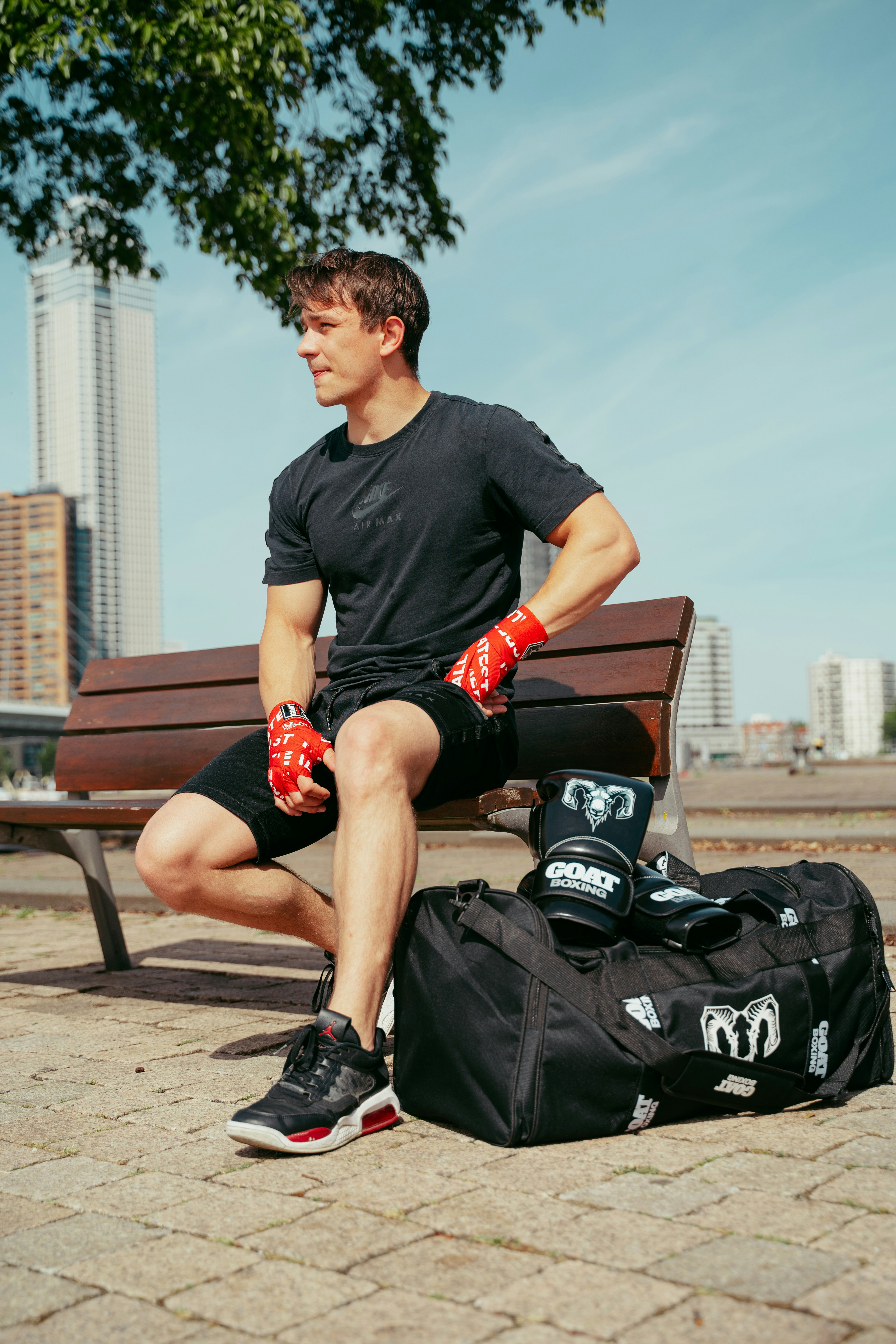 A man sitting on a bench next to a bag